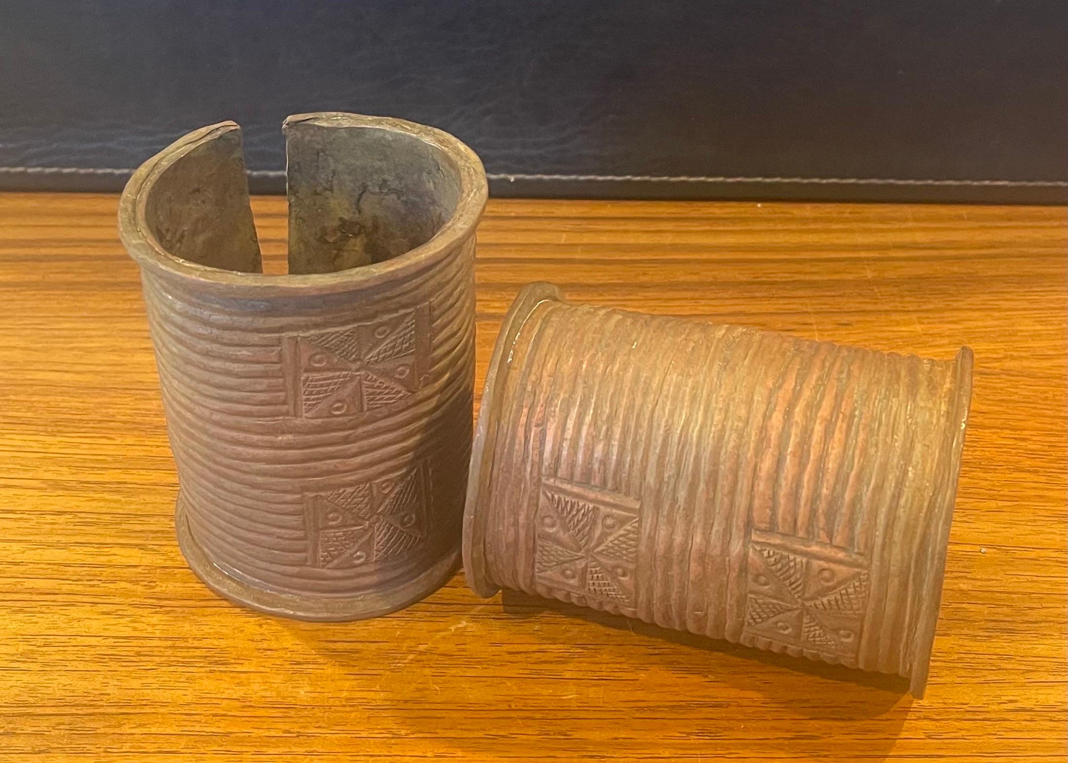 A very nice pair of African Igbo open-sided cast copper cuff bracelets, circa 1980s. The pair are a fine example of an open-sided cast copper cuff bracelet or wrist guard that is decorated with both geometric and figurative motifs etched and