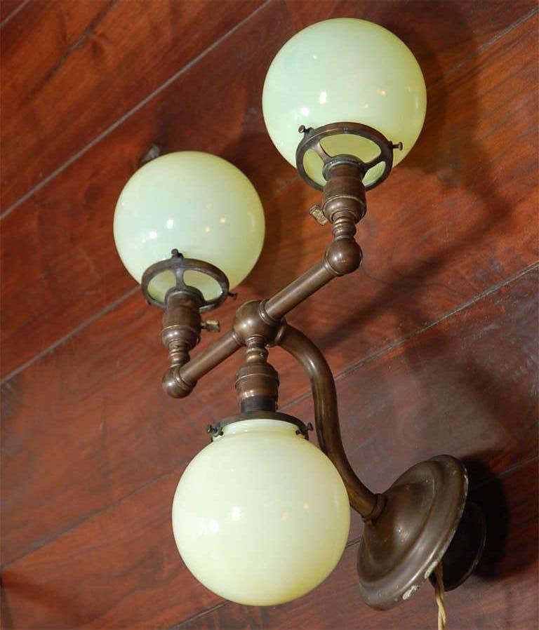 Pair of Aged Brass Sconces with Vaseline Glass Globes 'Triple' In Good Condition For Sale In Los Angeles, CA