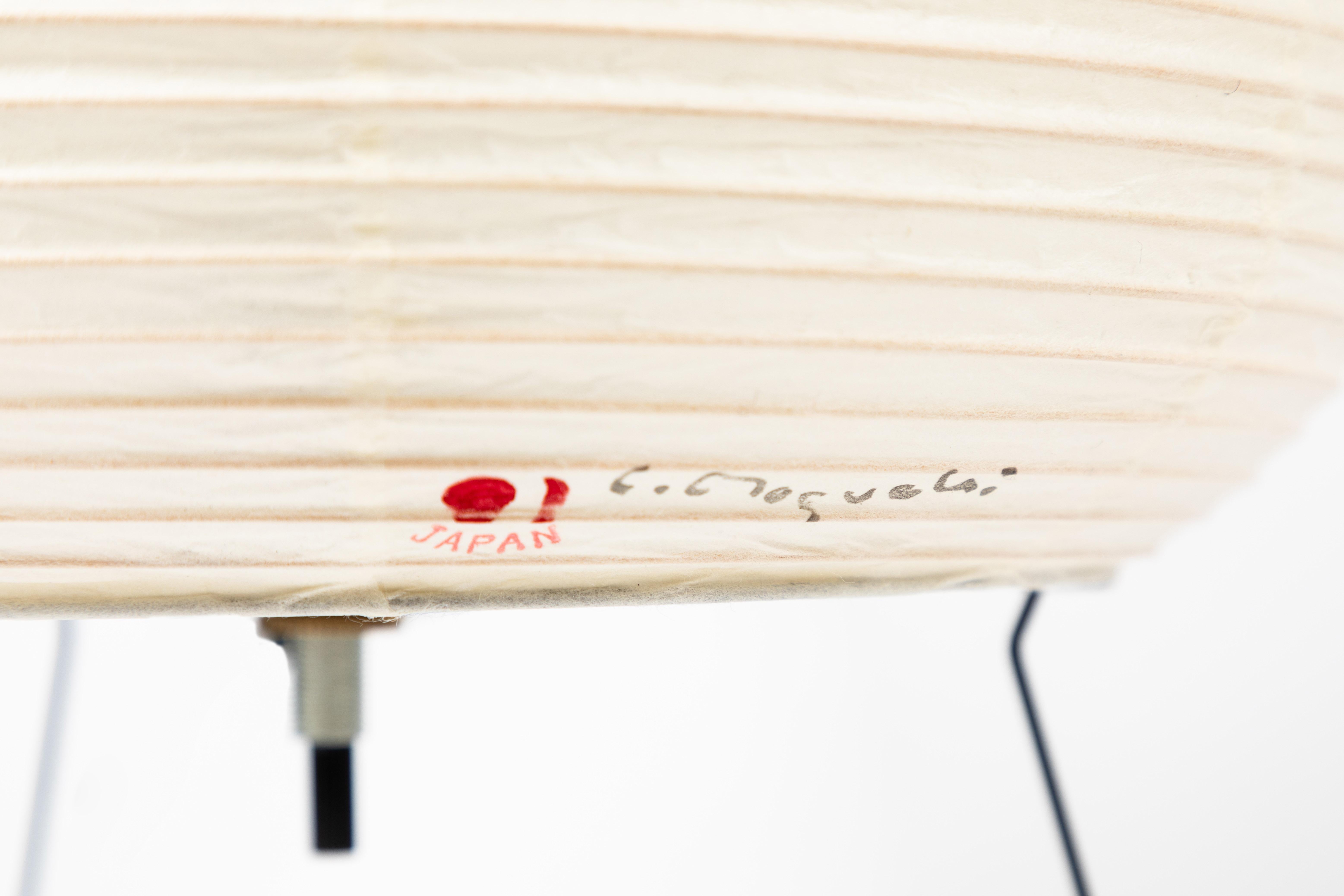 Pair of Akari model 1A light sculptures by Isamu Noguchi. The shades are made from handmade washi paper and bamboo ribs with Noguchi Akari manufacturer's stamp. Akari light sculptures by Isamu Noguchi are considered icons of 1950s modern design.