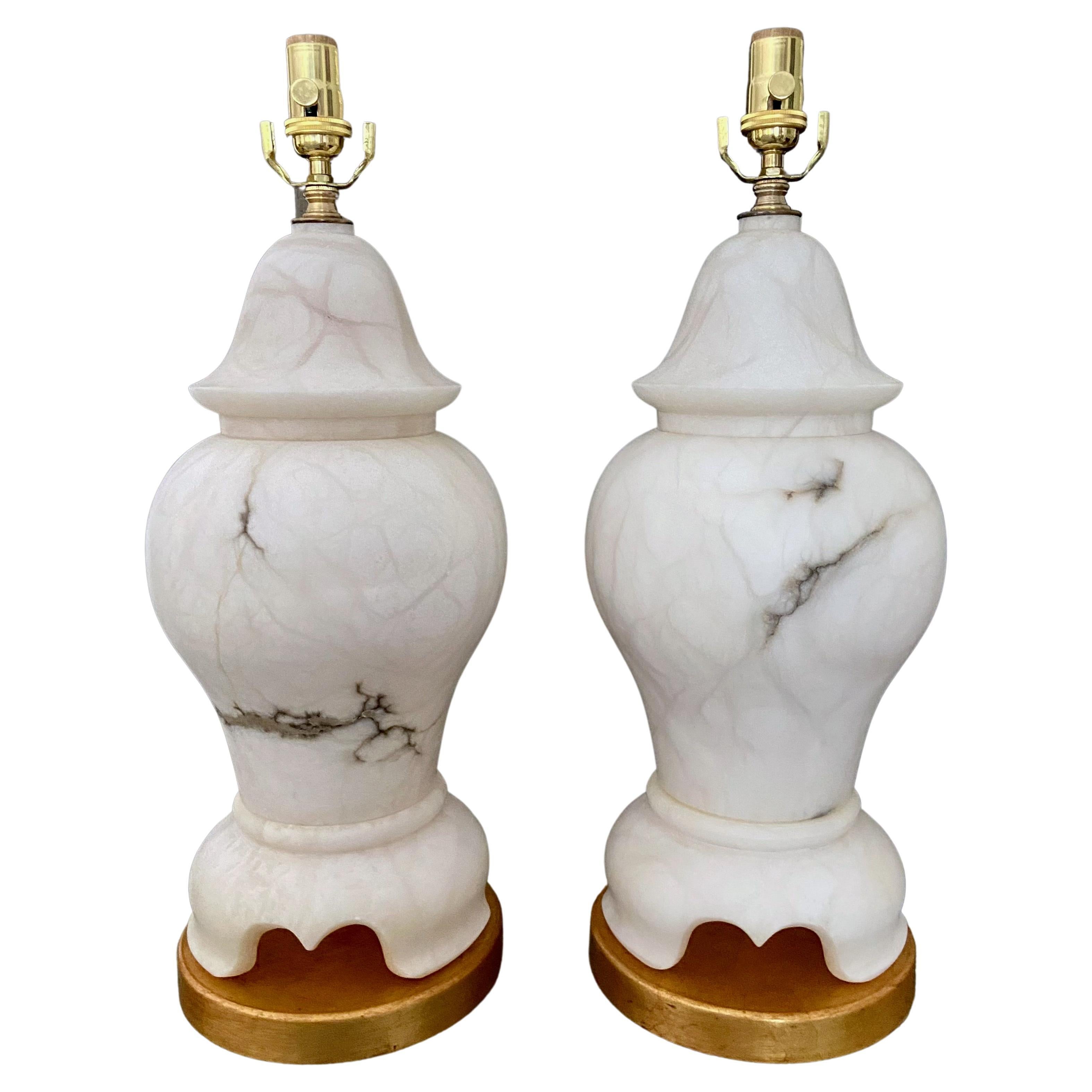 Pair of lidded urn form alabaster table lamps with brass fittings mounted on giltwood bases. Heavy and expertly constructed. Newly rewired with 3 way sockets and rayon covered cords. Included are alabaster finials for shades. Overall height top of