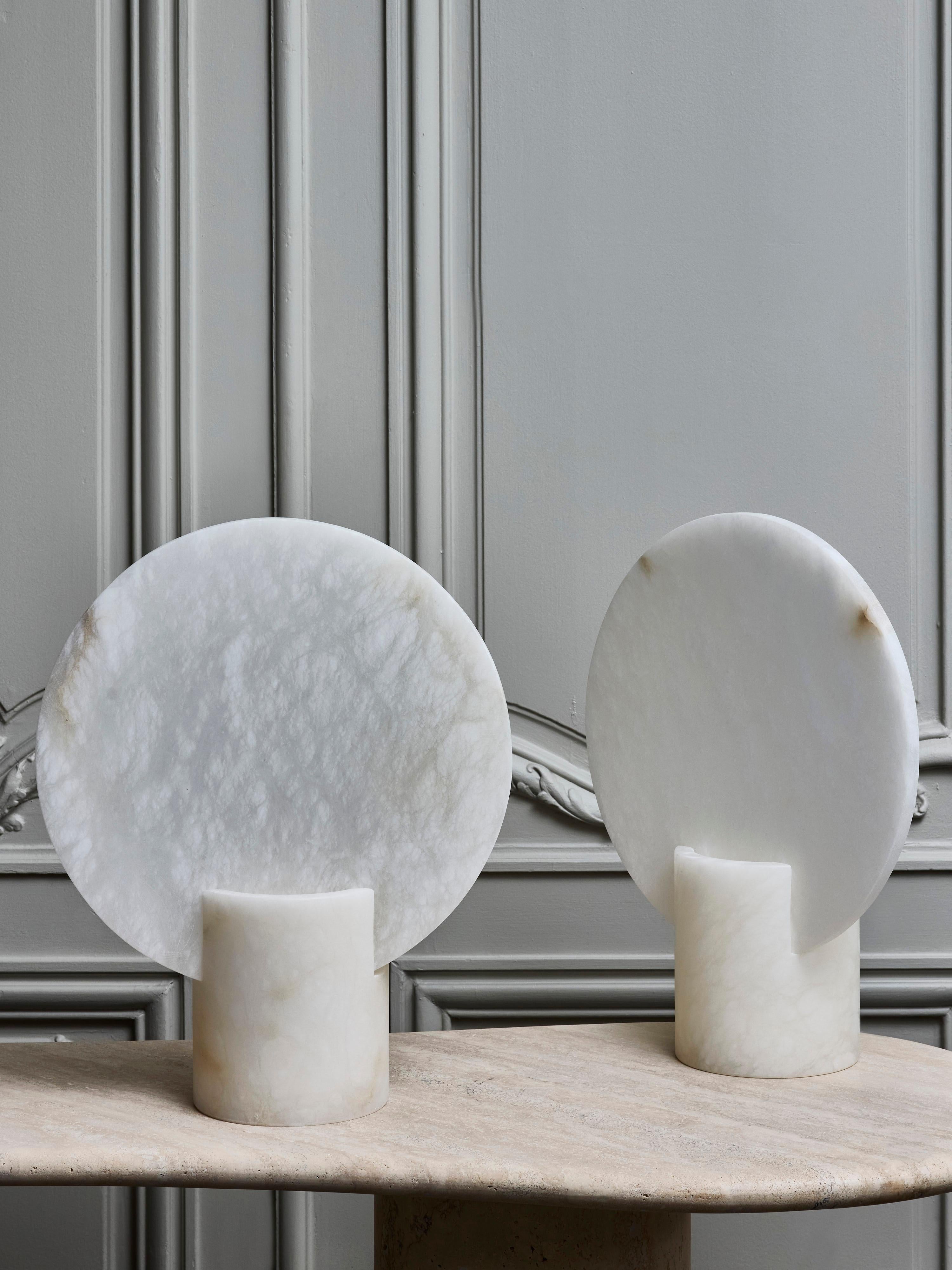 Paire de lampes de table en albâtre composées d'une base cylindrique à fentes supportant un grand diffuseur rond sur pied. Une source de lumière par lampe.