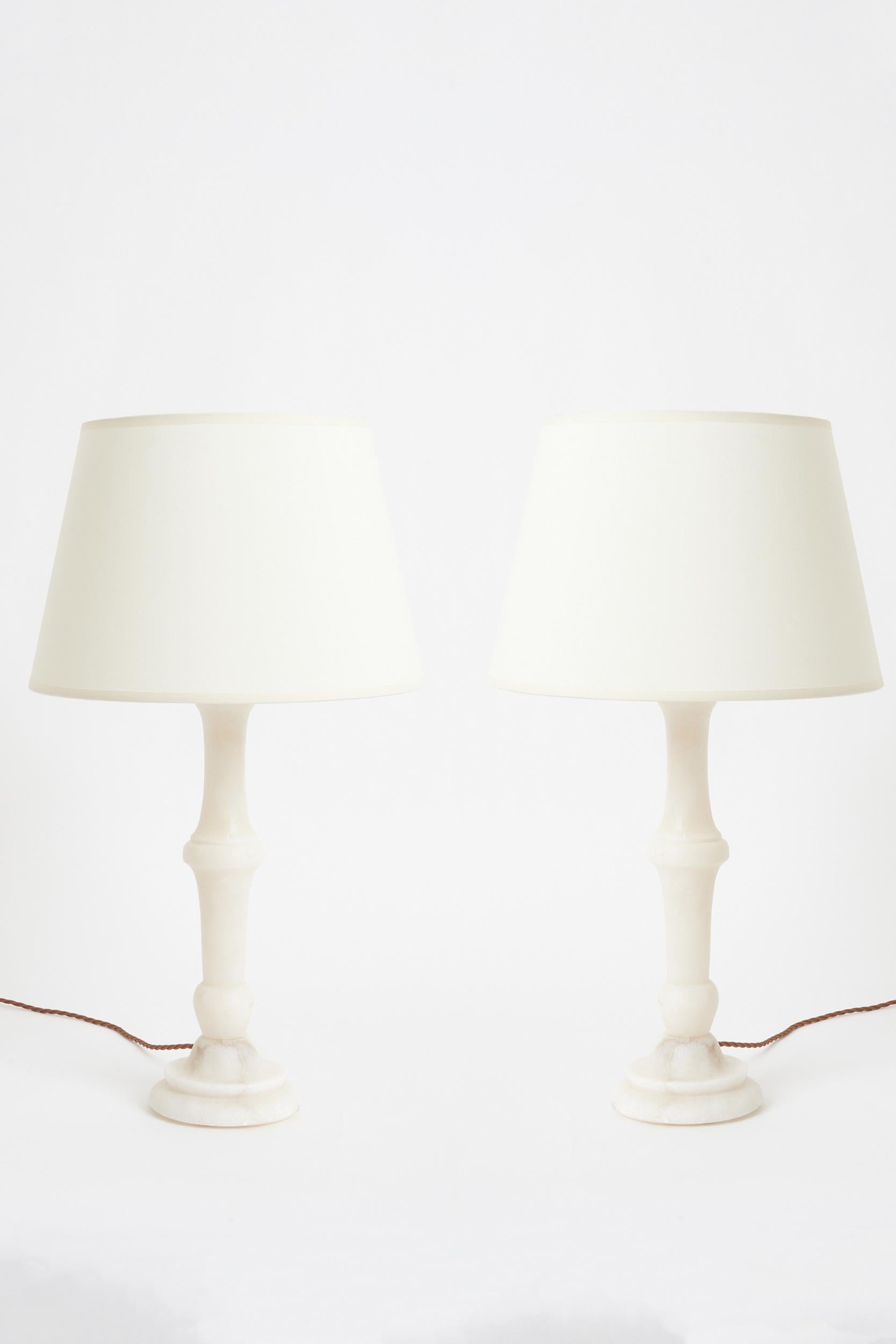 A pair of carved alabaster table lamps
Spain, mid 20th Century
With the shade: 64 cm high by 35.5 cm diameter
Lamp base only: 46 cm high by 15 cm diameter.
