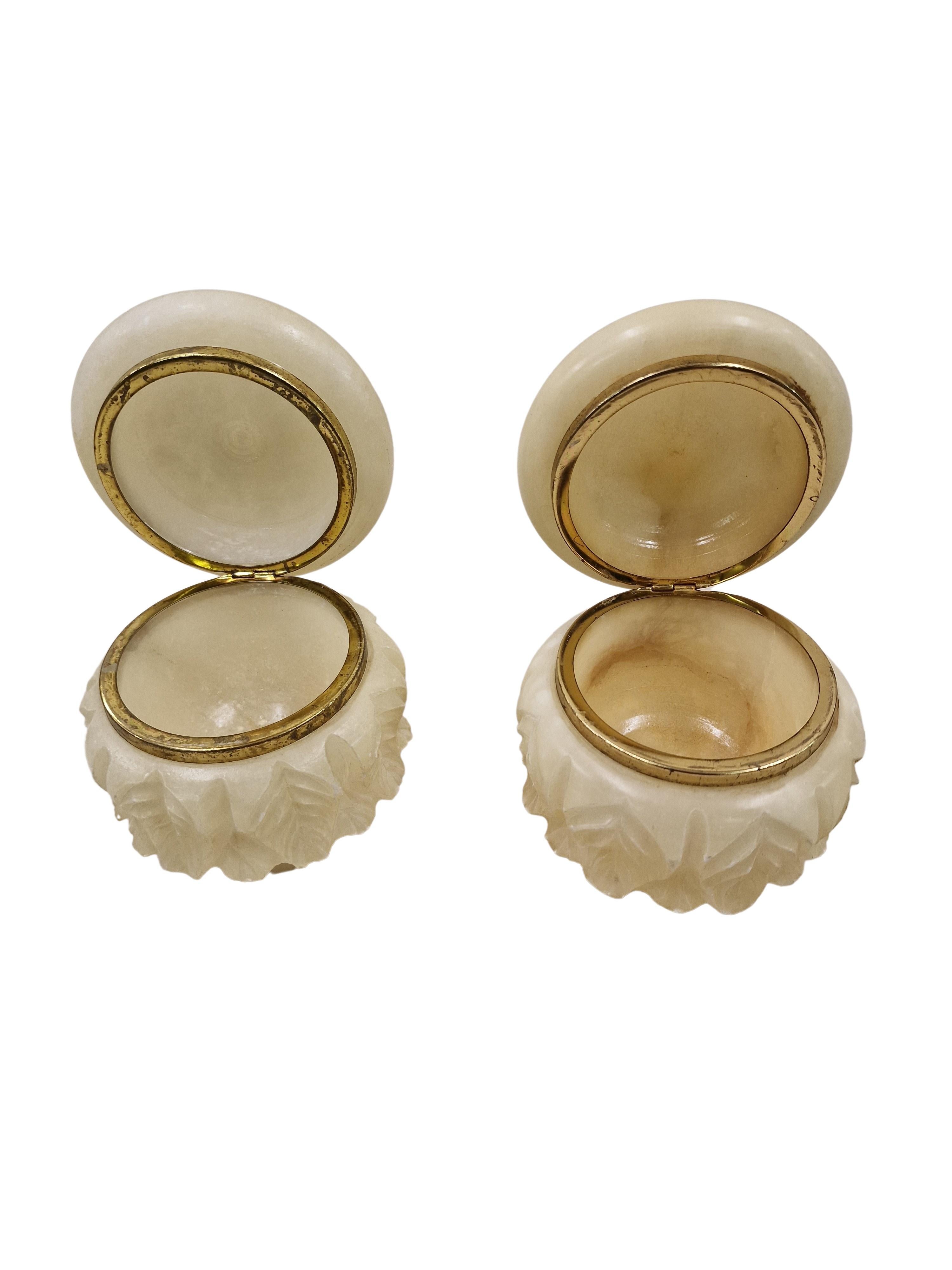 Pair of perfectly hand-cut lidded boxes out of white alabaster, made in the 1920s, in Italy. 
These objects have a round basic shape, but they have a cuff all around that is designed in the form of leaves. All hand carved into the alabaster. The
