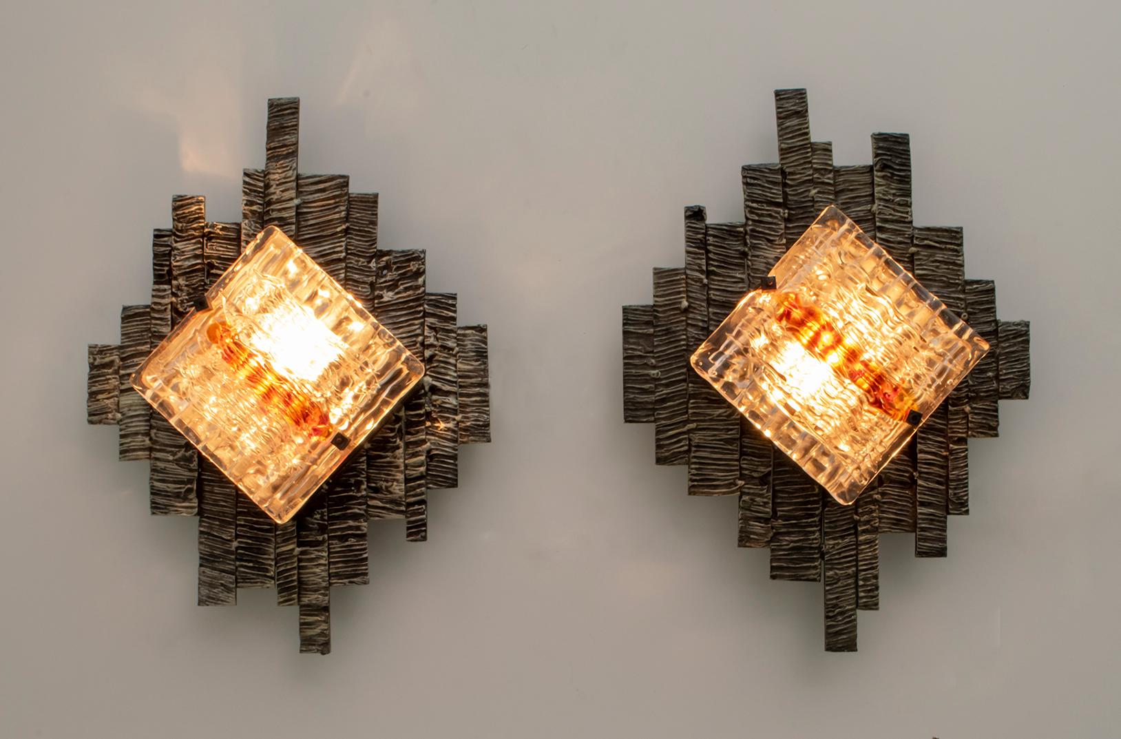 These wall lamps were created by the master glassmaker Albano Poli for his Poliarte company. The wall lamps have a patinated and handmade metal base, two squares in white relief glass with brick red serpentines. The sconces can be fixed vertically