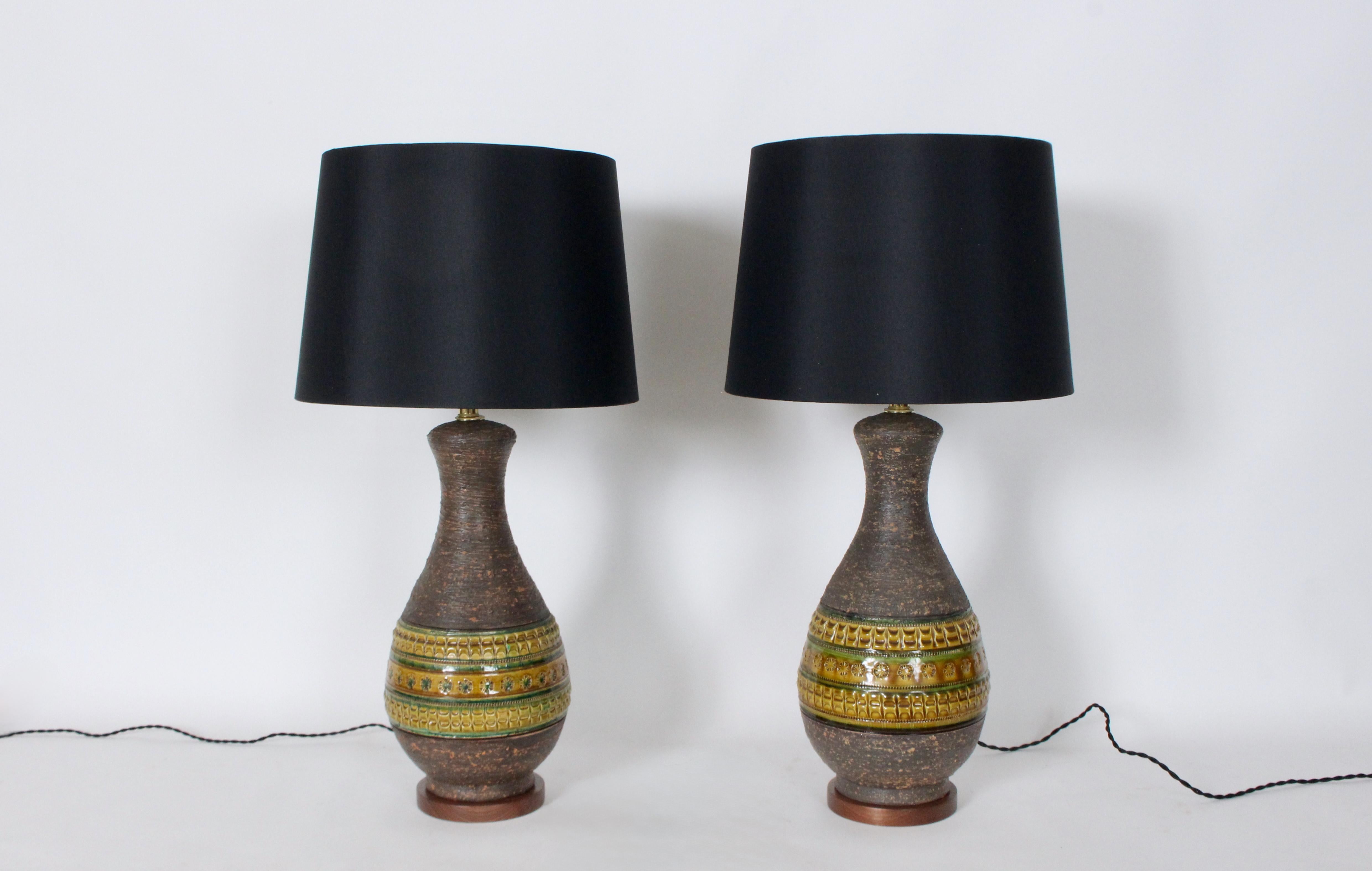 Pair Aldo Londi for Bitossi Horizontally Glazed Art Pottery Table Lamps. Featuring textured glazed Cocoa & Terracotta Ceramic imprinted bottle forms, Brass plated necks, hand applied stamping in alternating shades of Green, Mustard, Ochre, Brown
