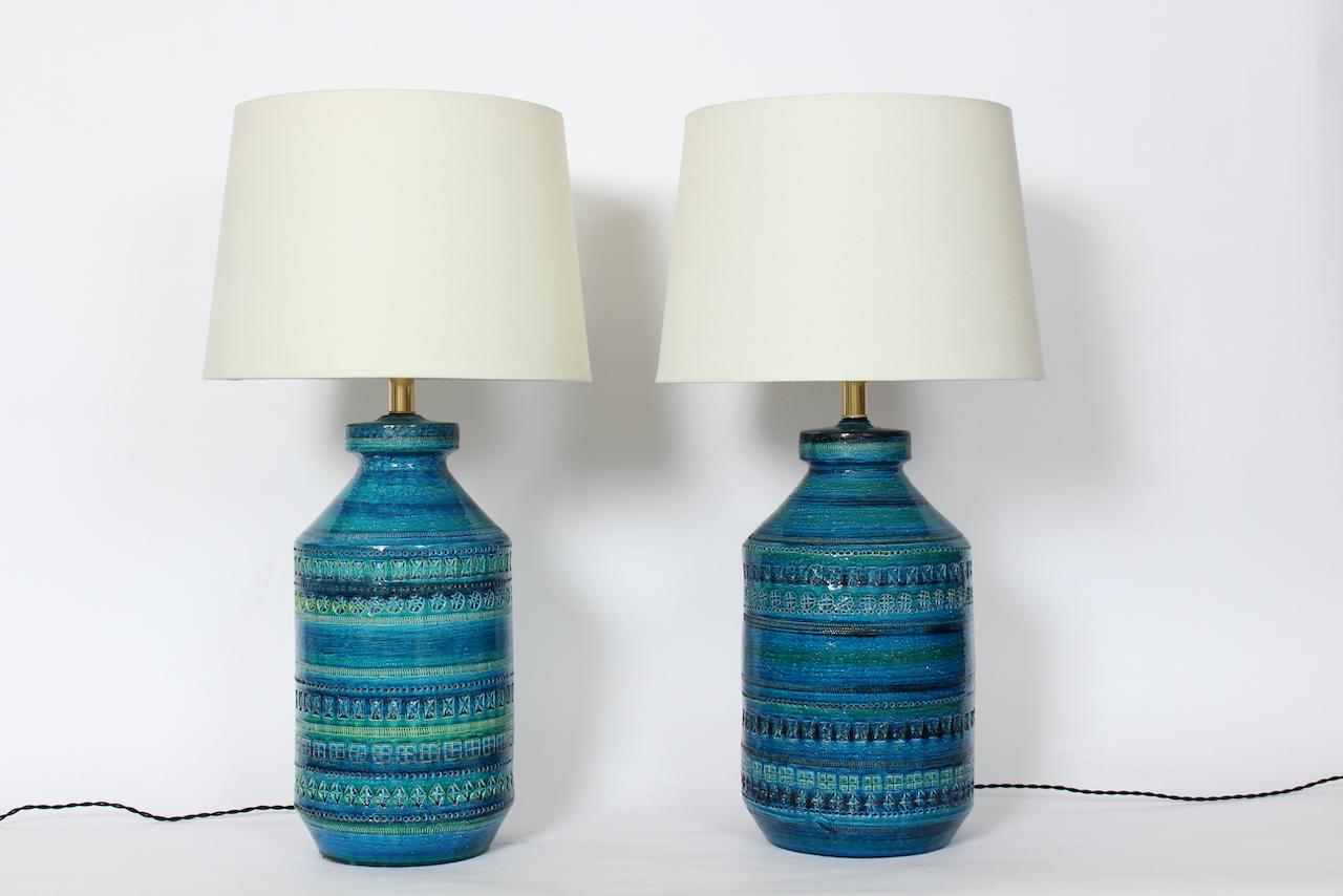 Pair Aldo Londi for Bitossi Imprinted Geometric Glazed Art Pottery Table Lamps. Featuring a textured glossy Ceramic bottle forms, Brass plated necks, with hand applied stamping in shades of Blue with Green banding. Showing slight variation in