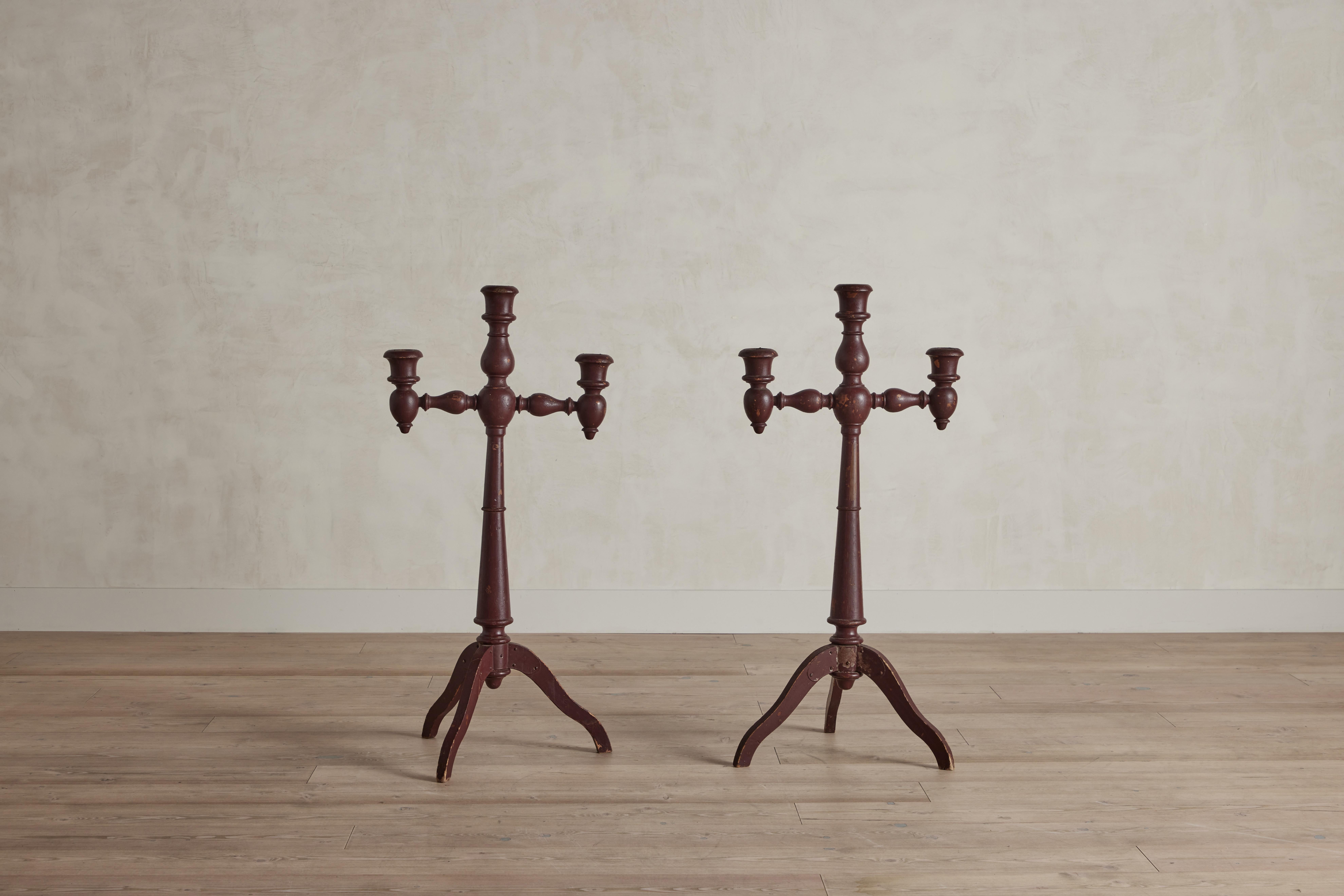 A pair of large red painted turned wood altar candlesticks from France circa 1850. Candlesticks measure 45.5” inches tall. Wear on wood and finish is consistent with age and use.