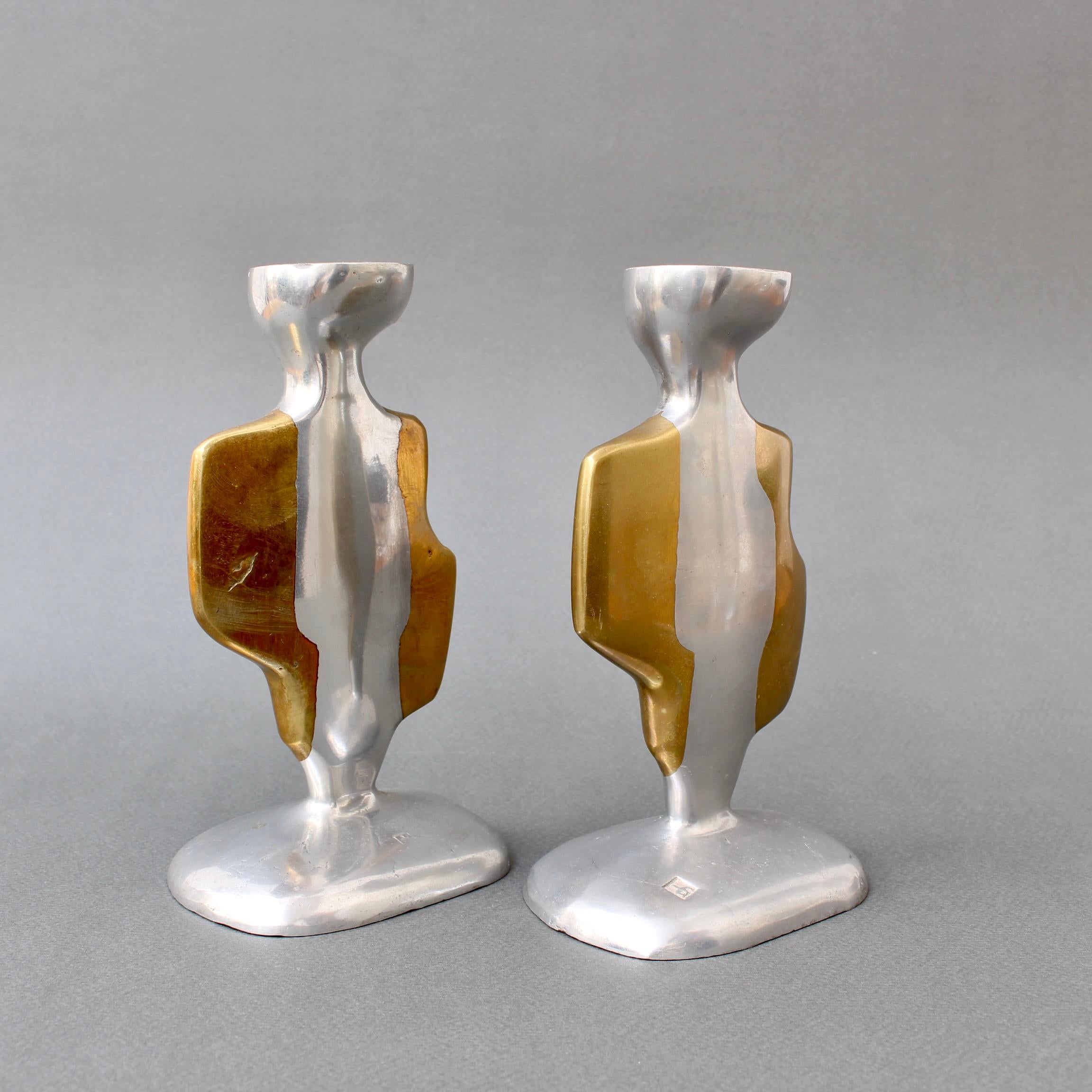 Pair of aluminium and brass candle stands by David Marshall (circa 1980s). Rather assuming human form, these curvy aluminium and brass candle stands have presence, weight and character. So attractive they can stand on their own in the room. Both the