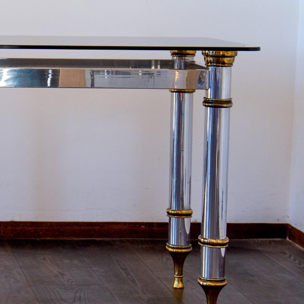A pair of rectangular Maison Jansen style, polished aluminium console tables with brass collar mounts and stilleto feet supporting dark glass tops, 1970s.

  
