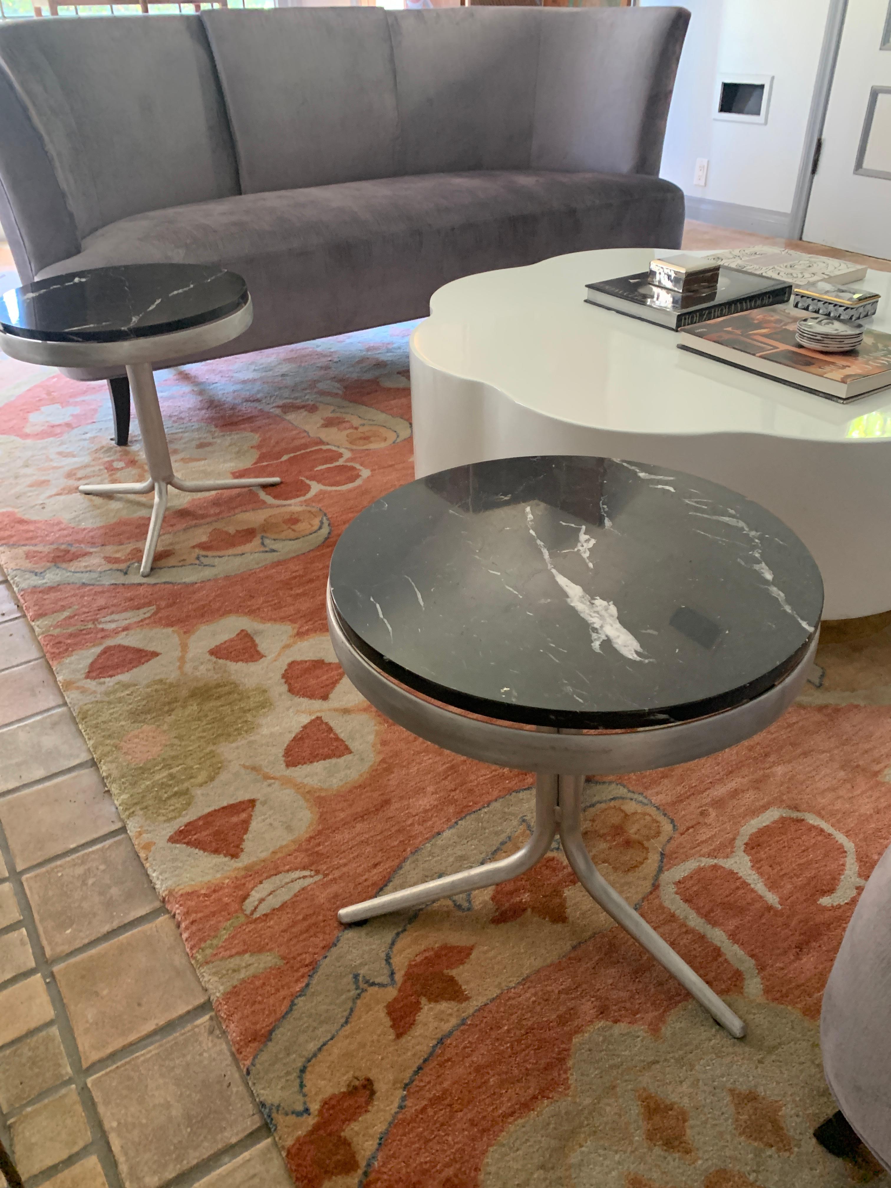 Sleek and architectural, a pair of side tables uniquely fabricated allowing three legs combined to house a sturdy aluminum ring. Floating atop the ring a black variegated marble disk.

The pair are believed to be prototypes, so likely one of a