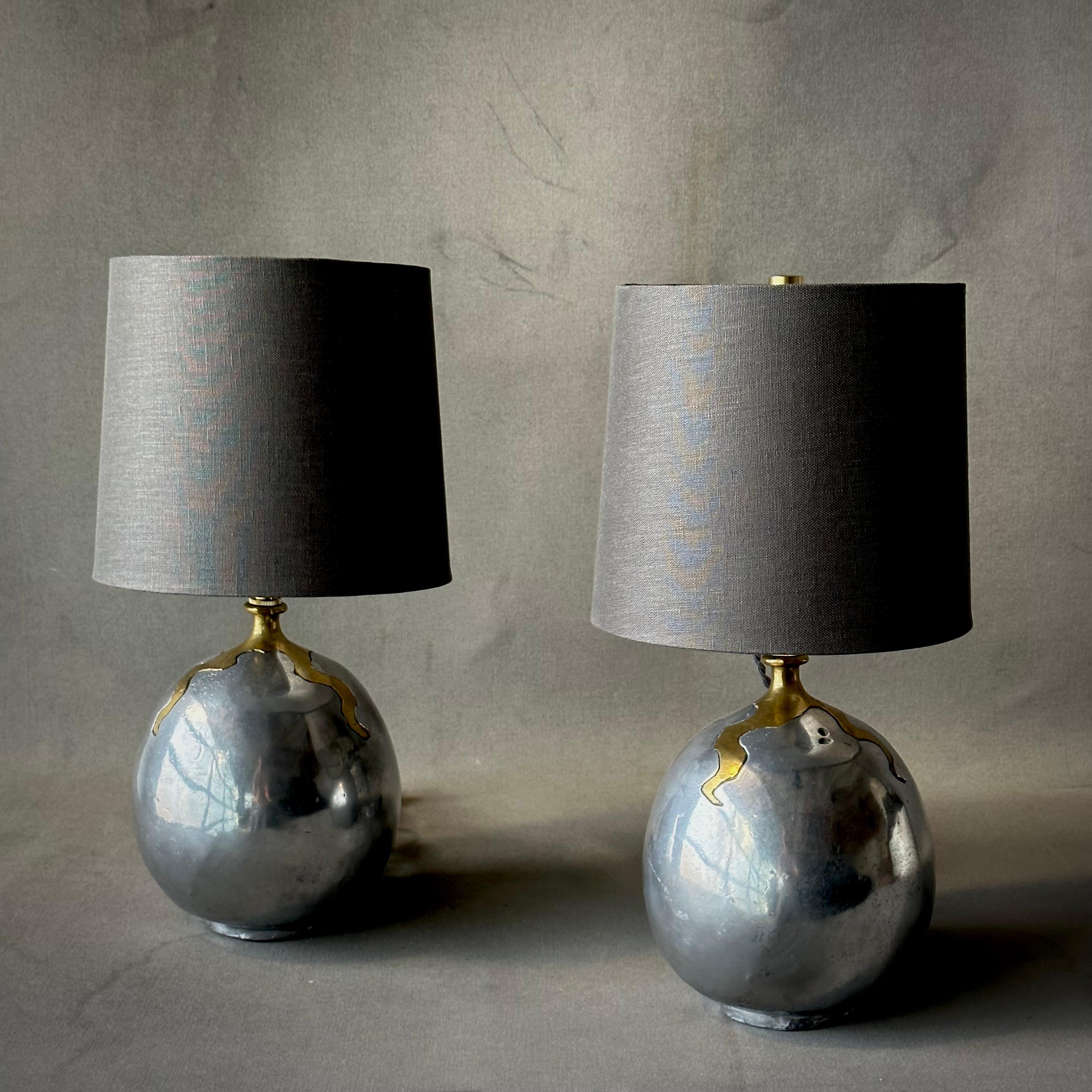 Pair of 1970s hand-cast brutalist aluminum table lamps by David Marshall. Strong yet organic, these versatile light fixtures are evocative of Elsa Peretti and Brancusi. Includes contemporary custom Belgian linen grdrum shades.

Spain, circa