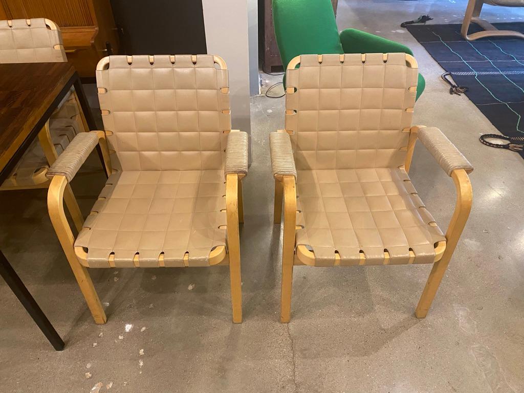Model 45 armchairs, designed in 1947 by Alvar Aalto and manufactured later by Artek. Beech frames and buff colored leather seat and back make a comfortable and sought after combination that is iconic to Scandinavian modern design. Original condition.