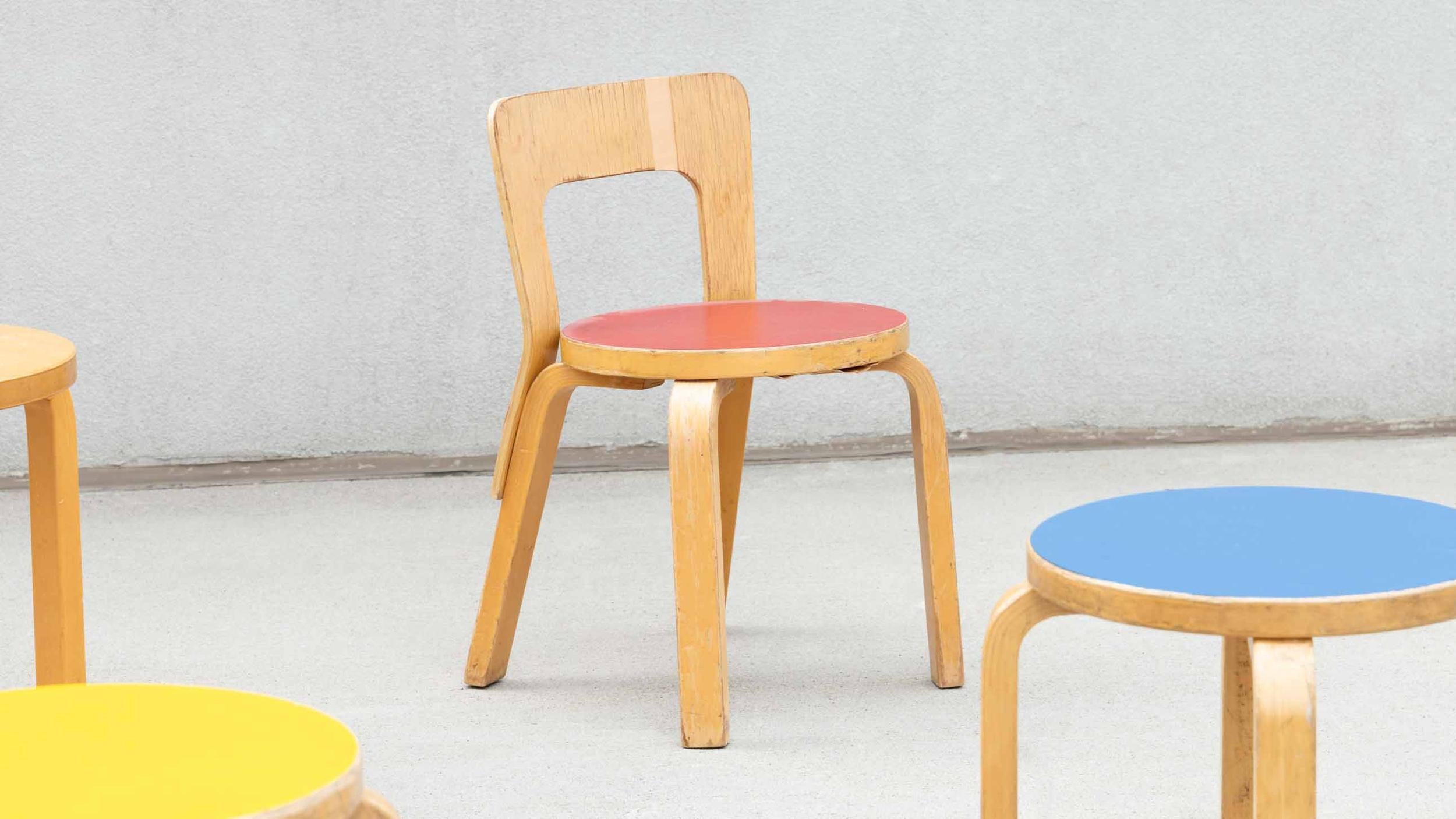 A pair of N65 chairs with red linoleum seats designed by Alvar Aalto for Artek, 1950s. Bentwood birch legs support a circular seat. Can be used for seating or as a plant or object stand. Substantial wear and use, as pictured.

color: light birch,