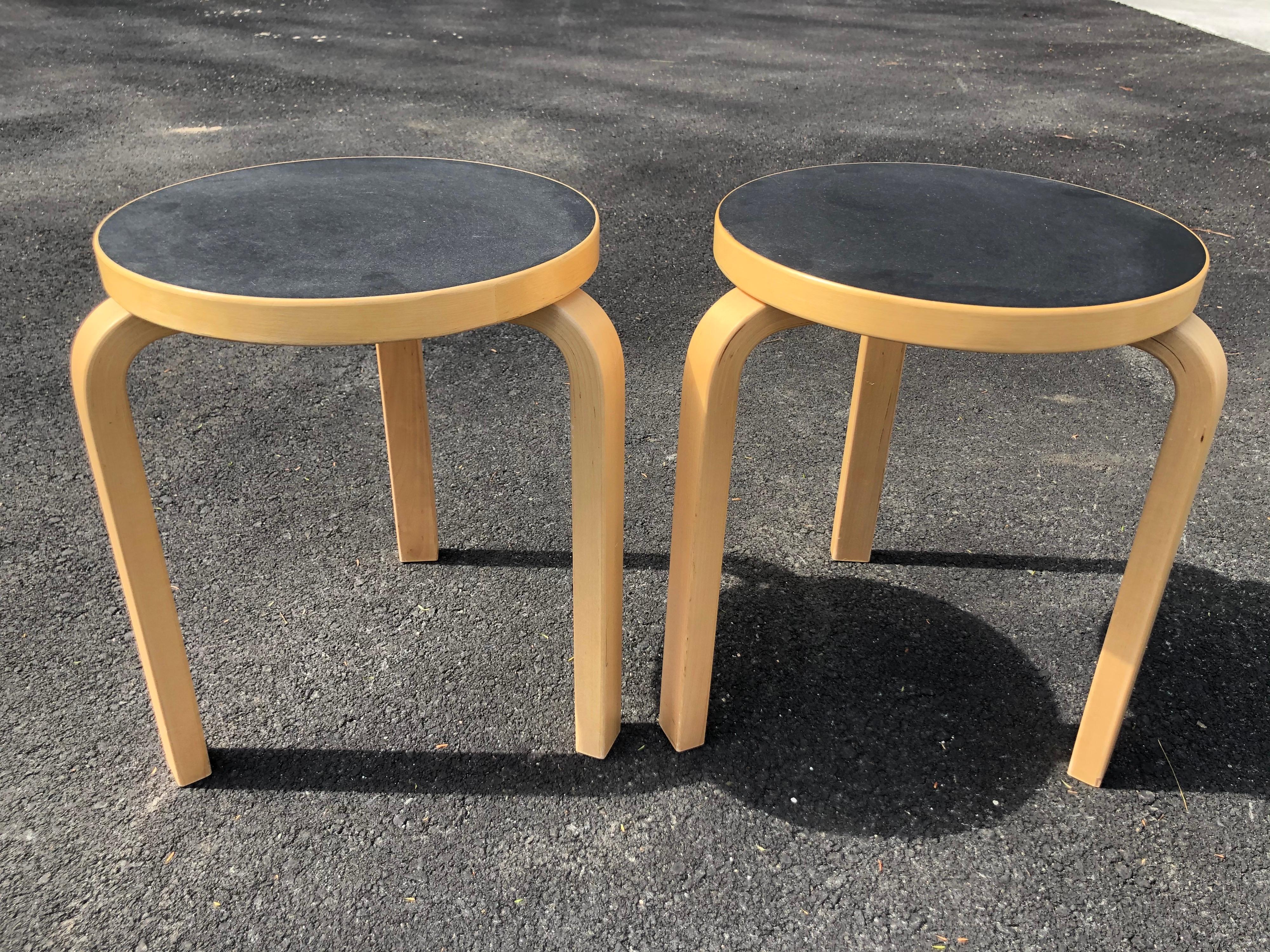 Pair of Alvar Aalto Mid-Century Modern round stools. Signed underneath ICF imports. Made in Finland.
These have black linoleum tops and three wooden legs and they stack. We believe this is Style# Stool 60.
Table top diameter is 13.50