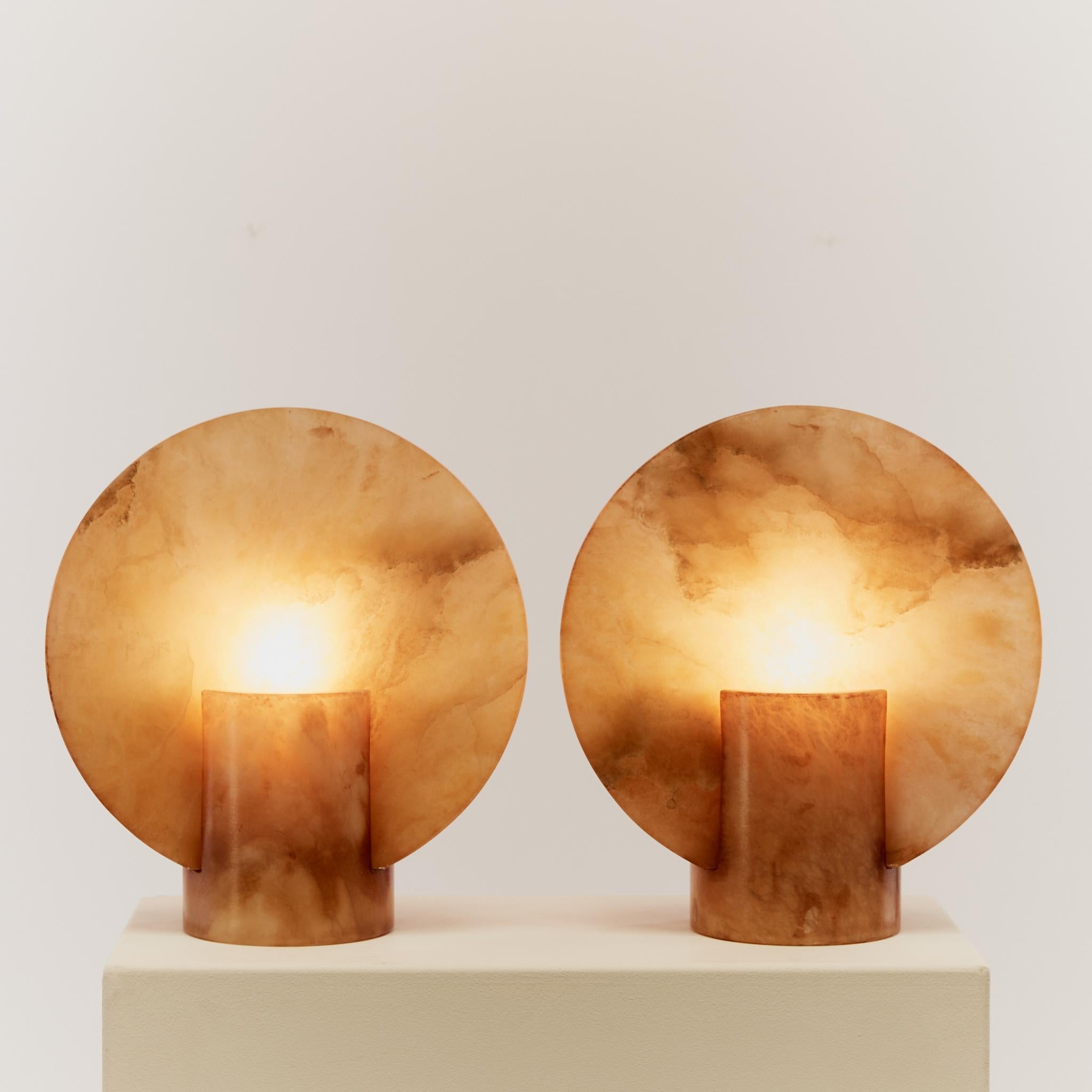 Pair of disc shaped lamps made from amber-toned alabaster. These sculptural lamps give a subtle ambient light and make a great statement pair on any console or mantel piece.

This pair come from a town in Spain that used to host an alabaster quarry