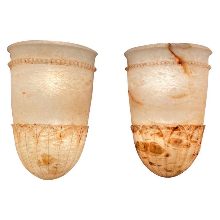 A neoclassic design, these urn shaped sconces feature a gracefully flared lip, a lower band of beading, and a cluster of laurel leaves surrounding the base.