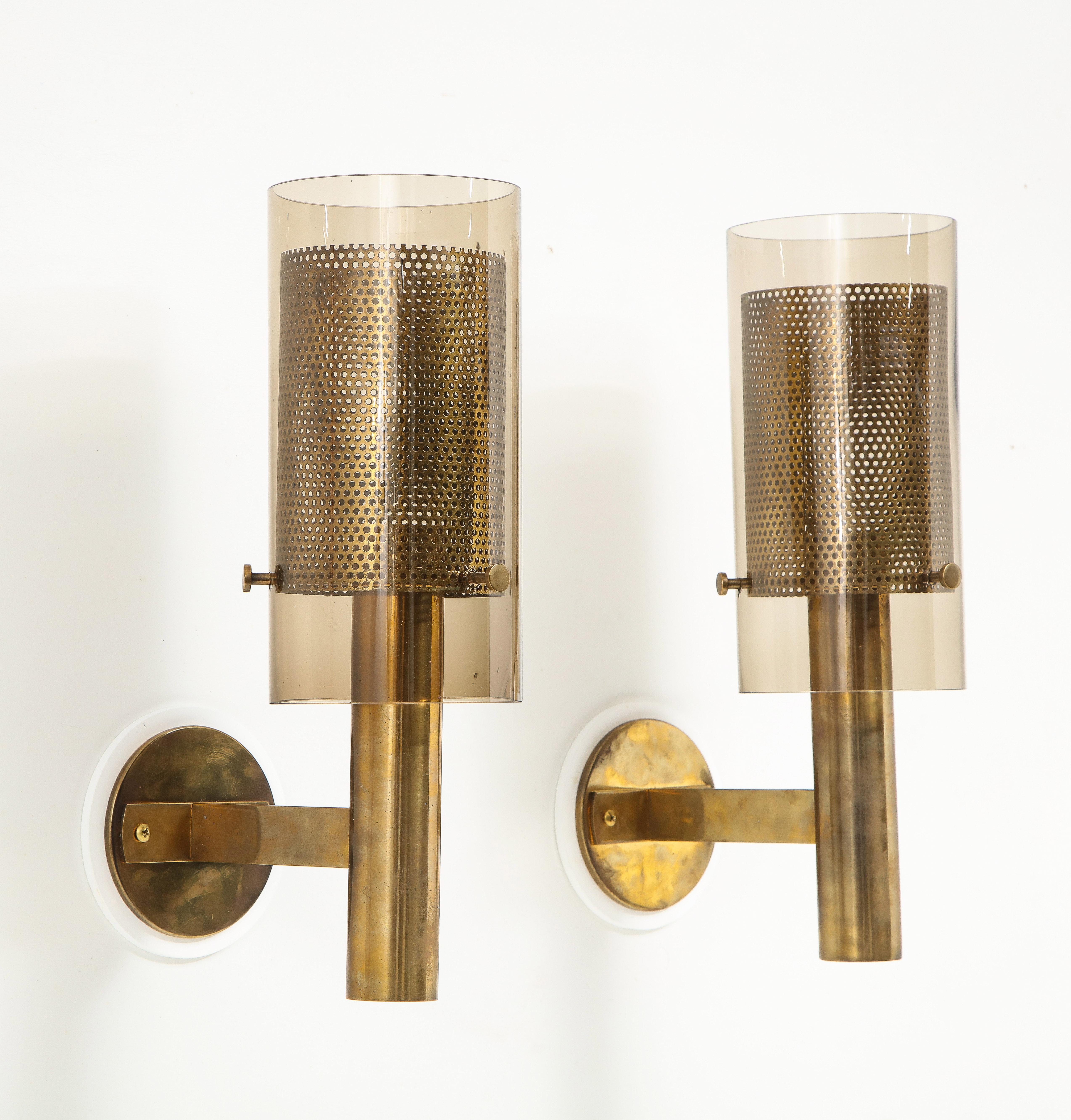 Elegant pair of single light sconces by Hans-Agne Jakobsson for Marakaryd of Sweden. The shades consist of a pierced brass sleeve within an amber glass shade held by three large machined screws.