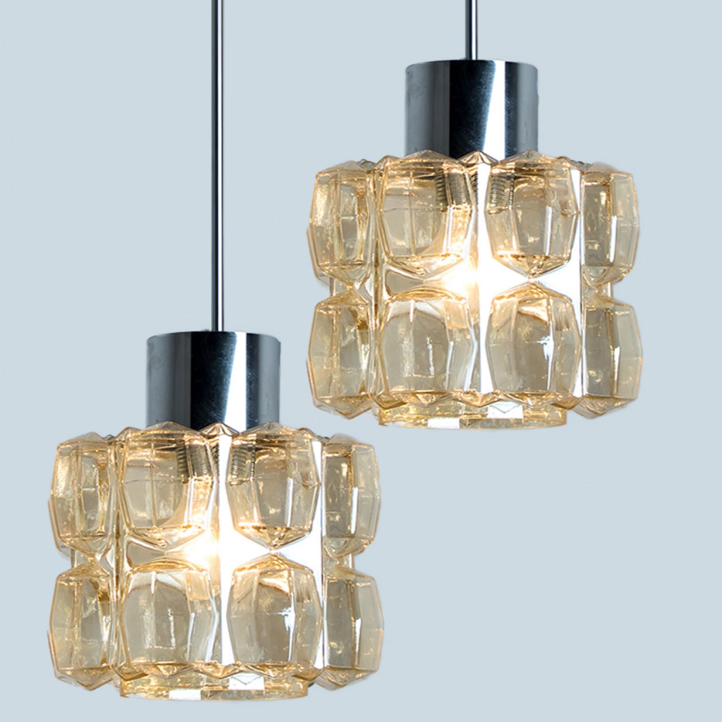 Pair of beautiful bubble glass and chrome chandelier or pendant light designed by Helena Tynell for Glashütte Limburg. A design Classic, the amber colored/toned hand blown glass gives a wonderful warm glow.

Helena Tynell is a finish glass and