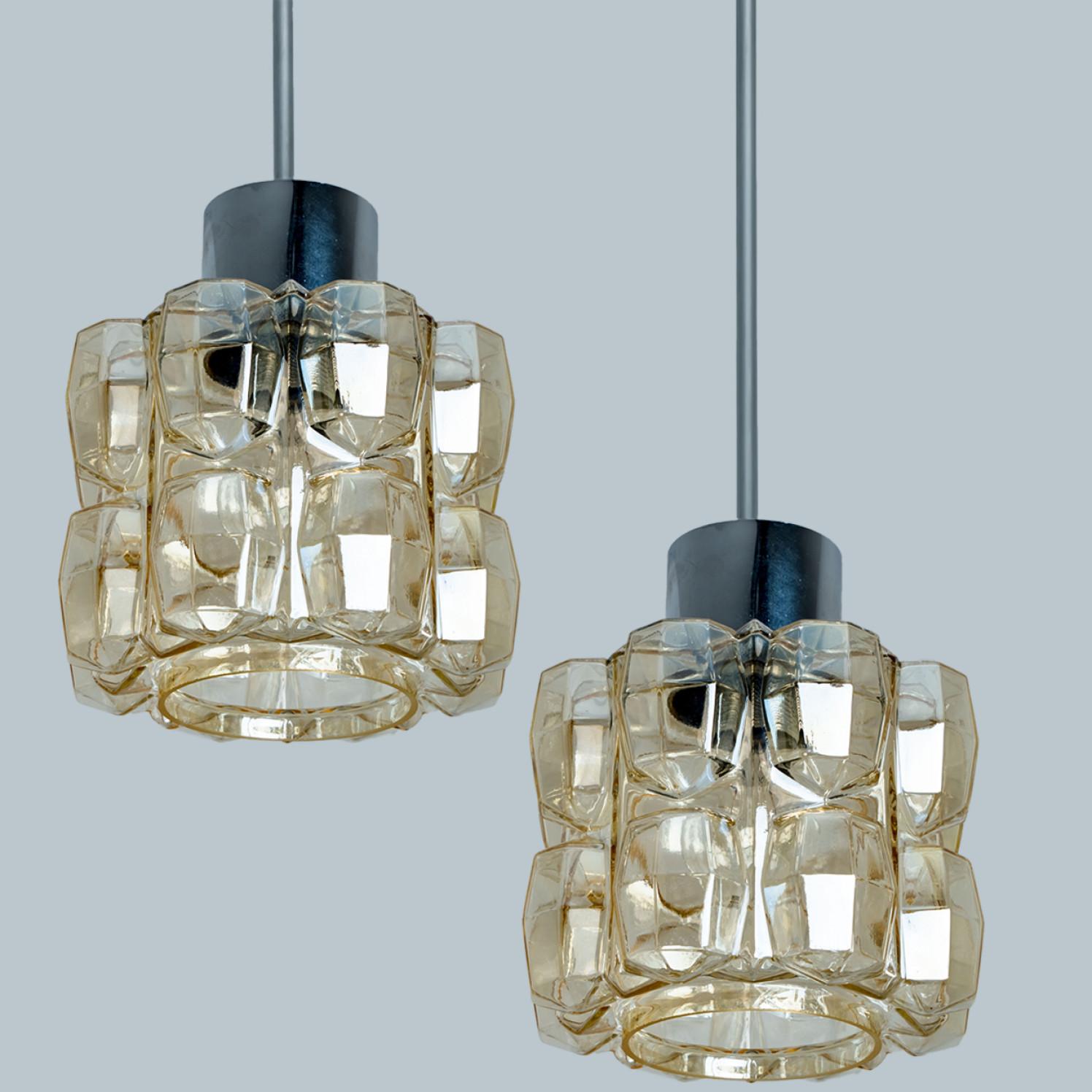 Coppia di bellissimi lampadari o lampade a sospensione in vetro a bolle e cromo disegnati da Helena Tynell per Glashütte Limburg. Un classico del design, il vetro soffiato a mano di colore ambrato/tonico dona una meravigliosa luce calda.

Helena