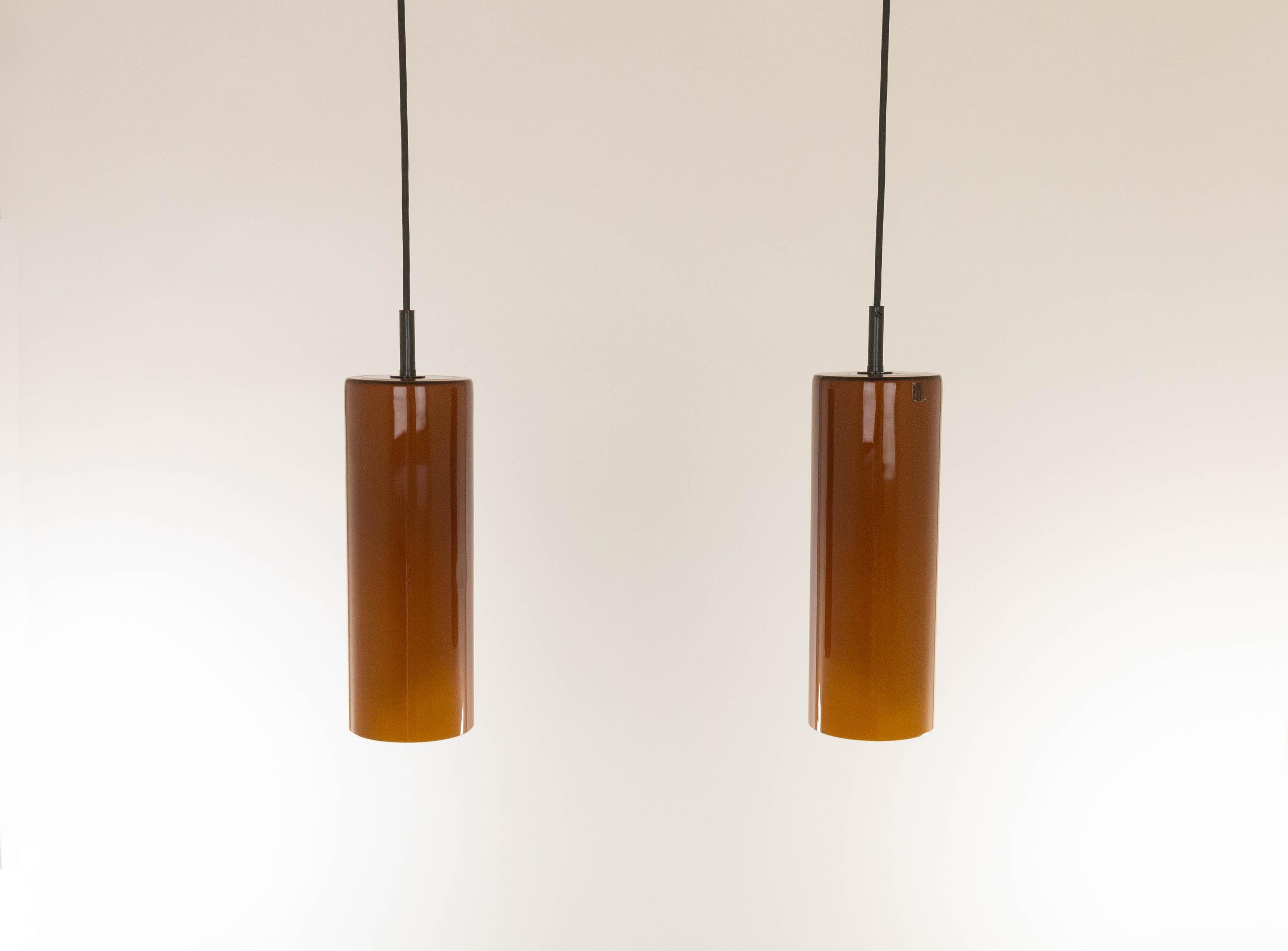 A pair of amber cylinder shaped glass pendants designed and produced by Murano glass specialist Venini.

The internal part with the bulb holder indicates that these lamps are from the 1980s.

Both pieces have parts of the original Venini sticker