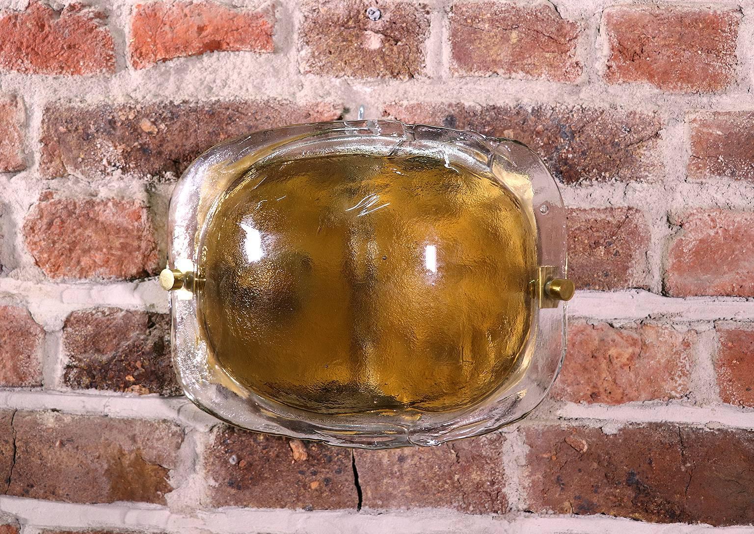 Elegant pair of wall sconces with thick amber Murano glass elements on a brass frame. Manufactured by Kaiser Lighting, Germany in the 1960s. 

Design: Carlo Nason attr. 
Maker: Mazzega. 
Manufacturer: Kaiser Leuchten. 
Lighting: takes one large