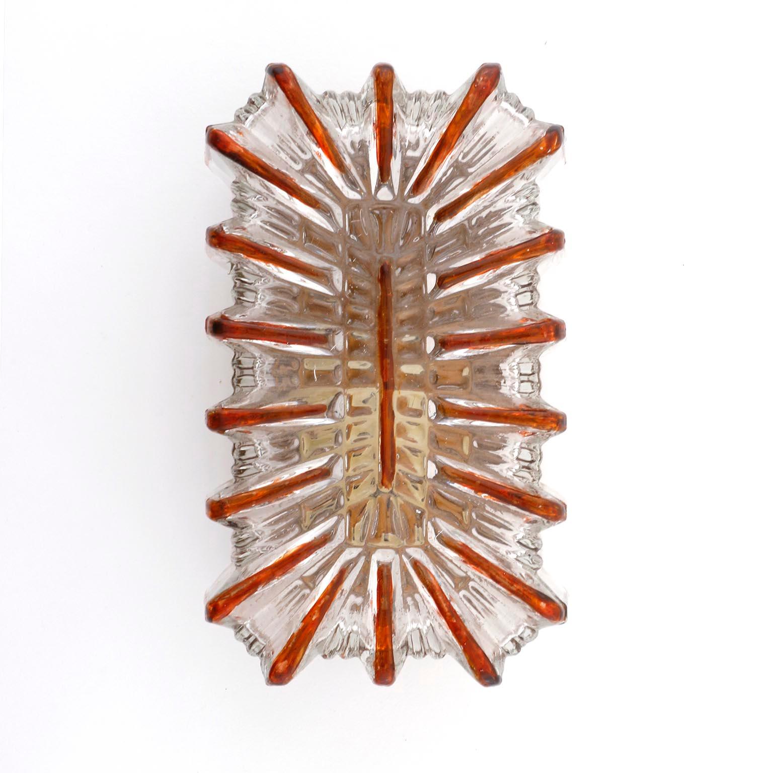 A German pair of vintage wall light fixtures in the style of Glashütte Limburg, manufactured in Midcentury, circa 1970 (late 1960s or early 1970s).
A reactangular, textured, clear glass with an embossed sunburst pattern in an amber color and a gold