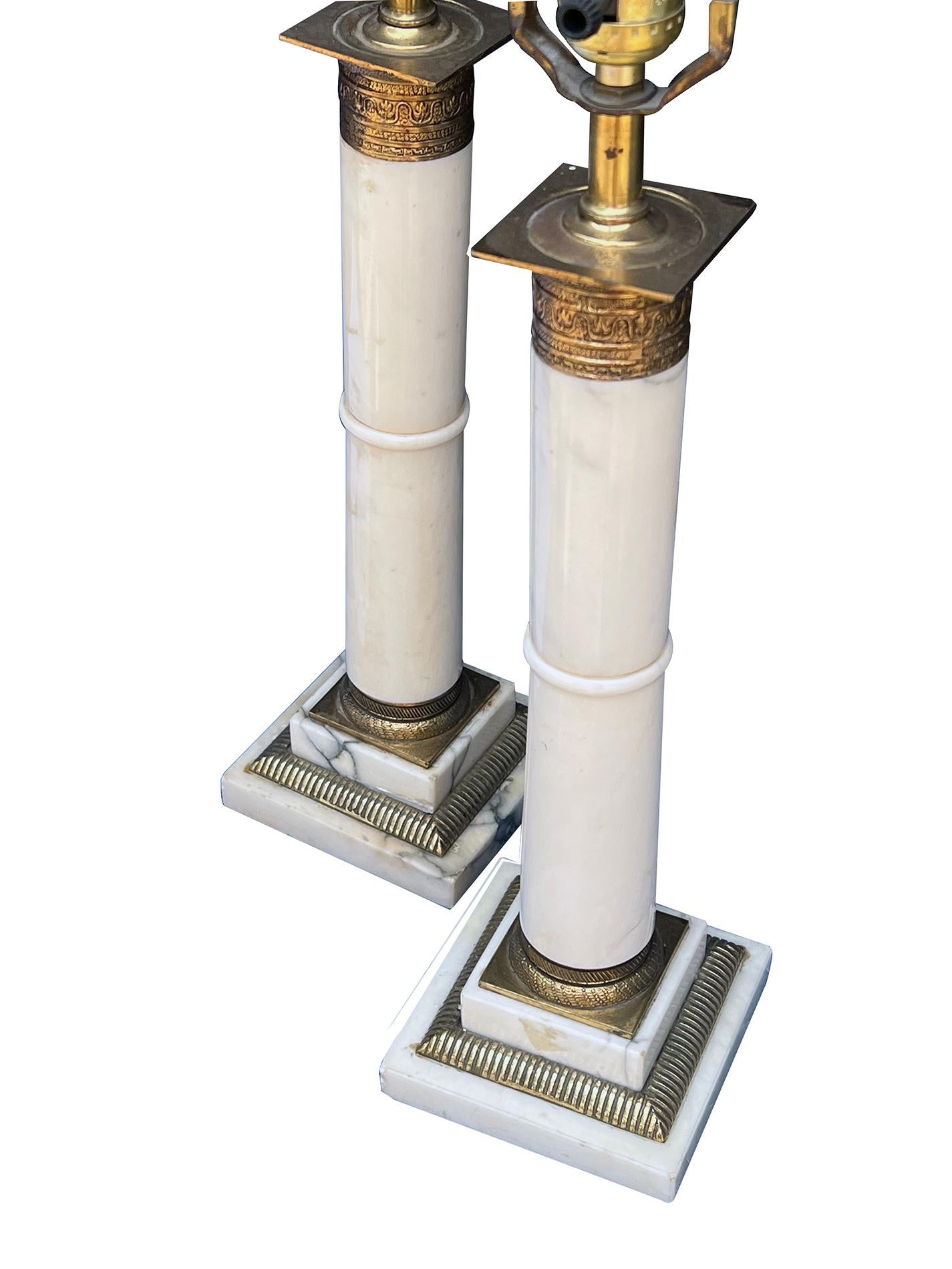 each column of Italian Carrara marble with raised perimeter band all over a stepped base adorned with gilt metal capitals and brass fittings at the base