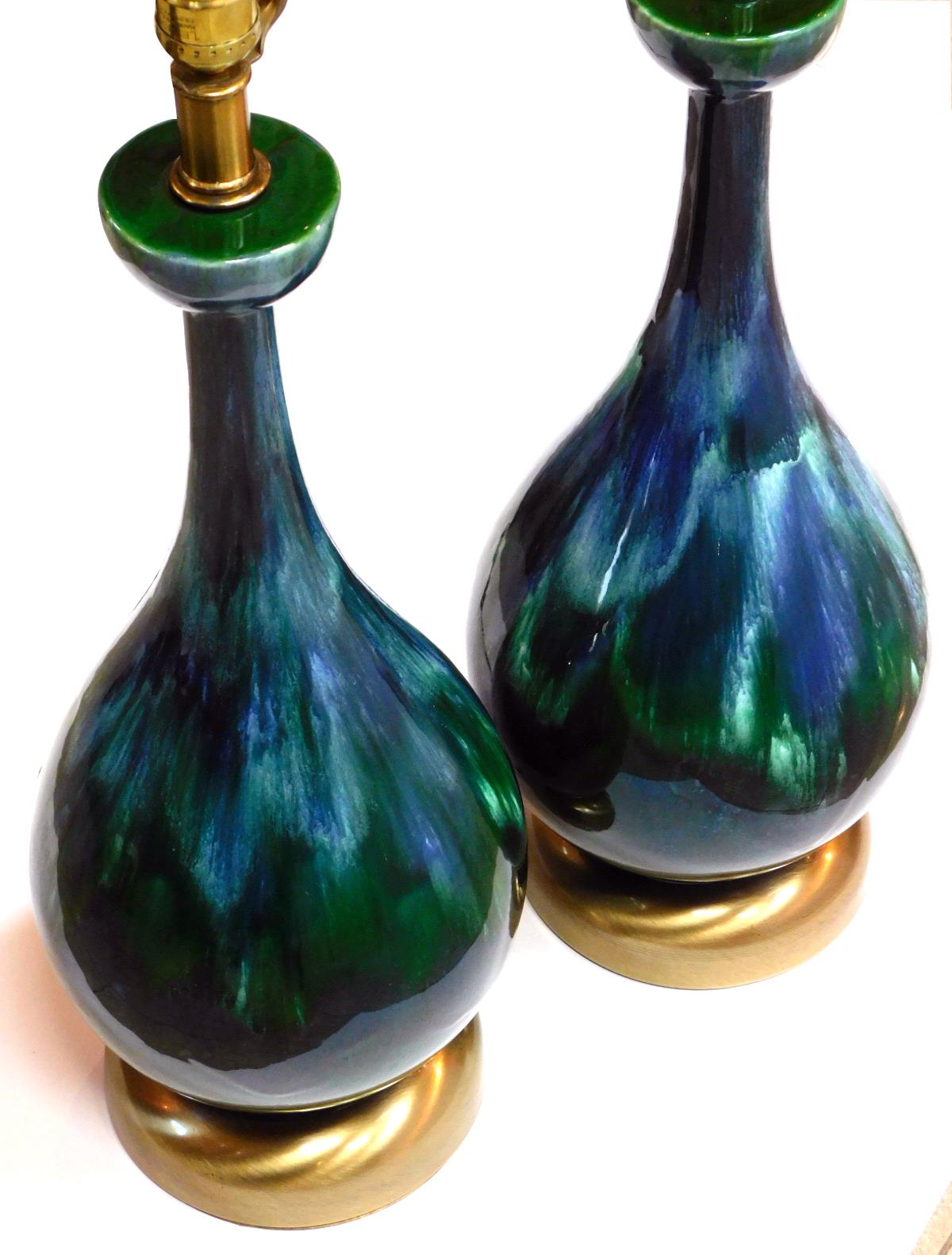 Each tall lamp with striking drip glaze in deep greens and blues; raised on a brushed brass base.