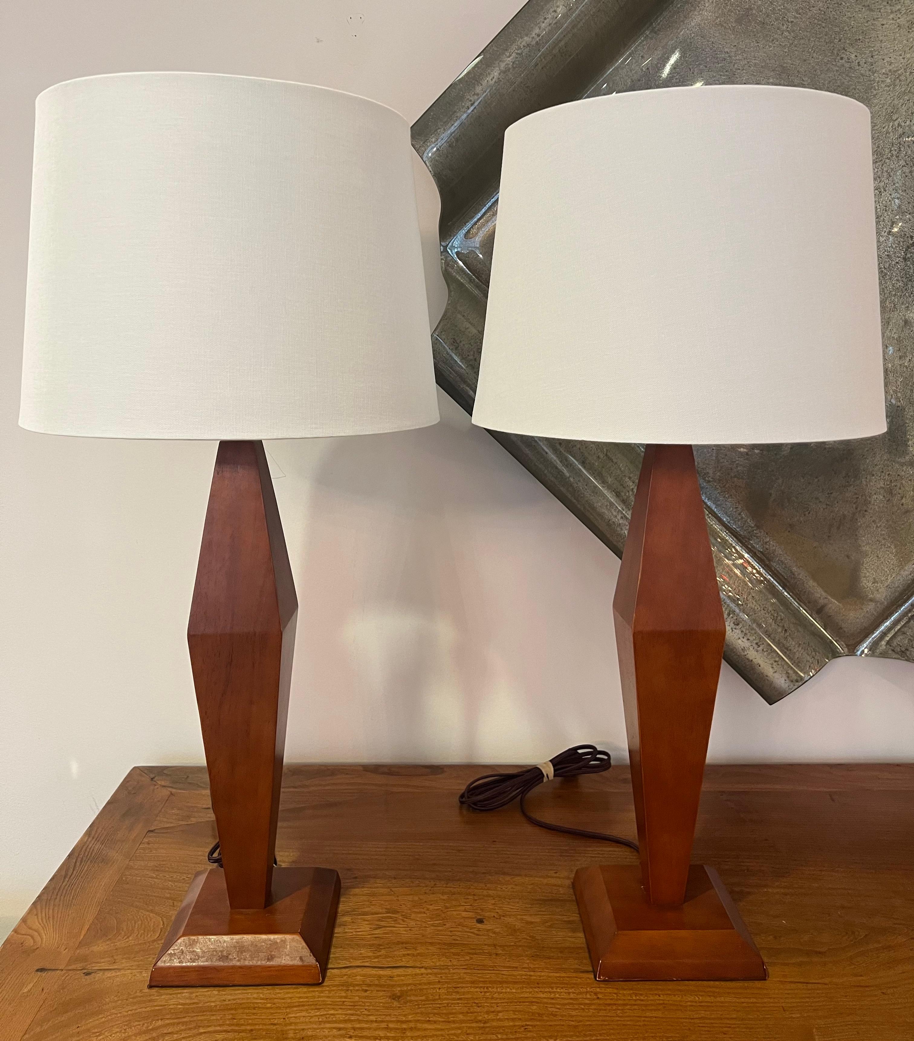 Paire  Lampes de table en bois sculpté de style Art Déco américain avec doubles douilles en laiton vieilli et cordons en tissu marron. Recâblé. Nous pouvons proposer les nuances à titre de référence. 