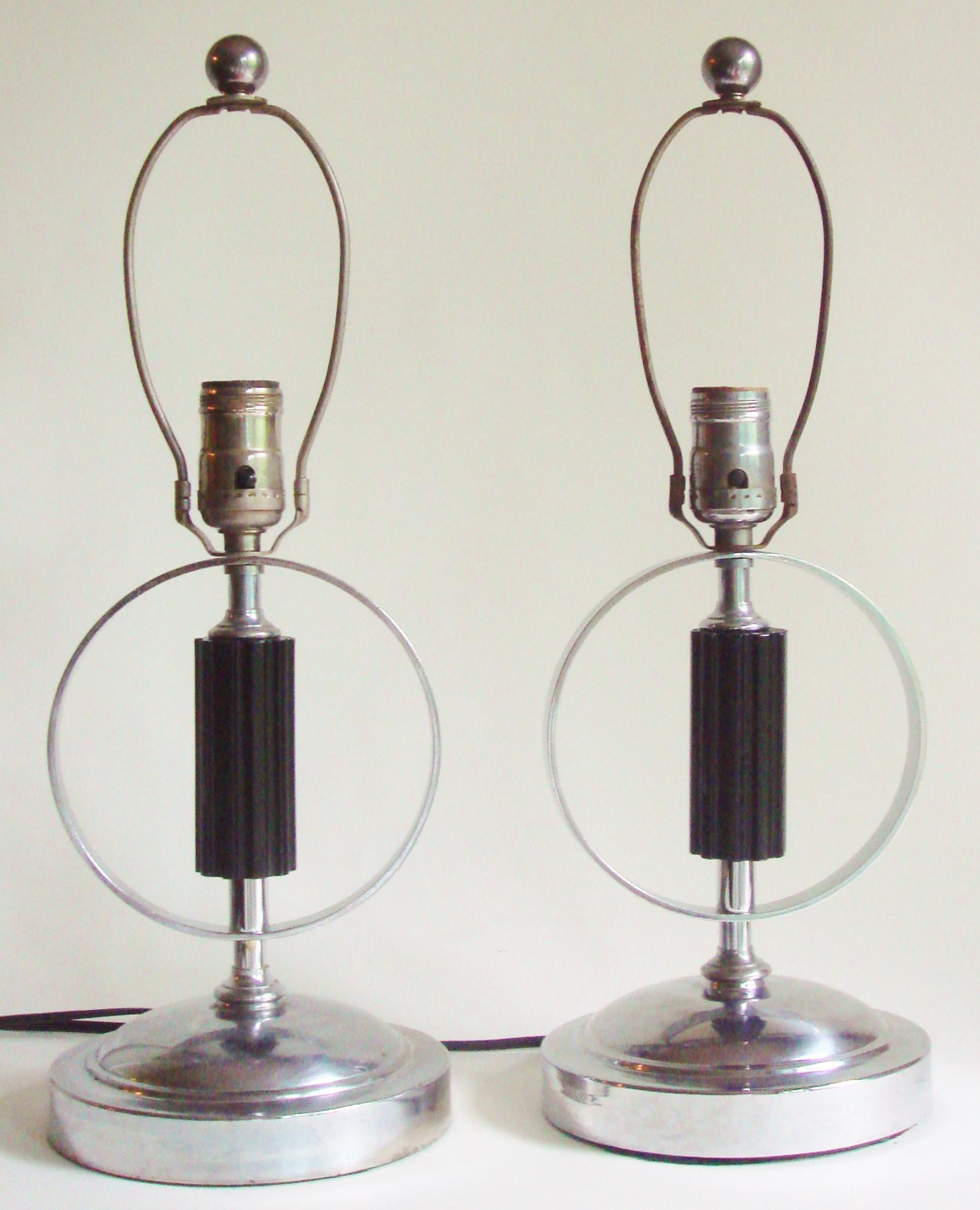 This striking pair of American Art Deco/Machine Age table or console lamps each feature a stepped and domed circular base. The main chrome shaft of each of the lamps is interrupted by a black lacquered and fluted wooden column fragment that is