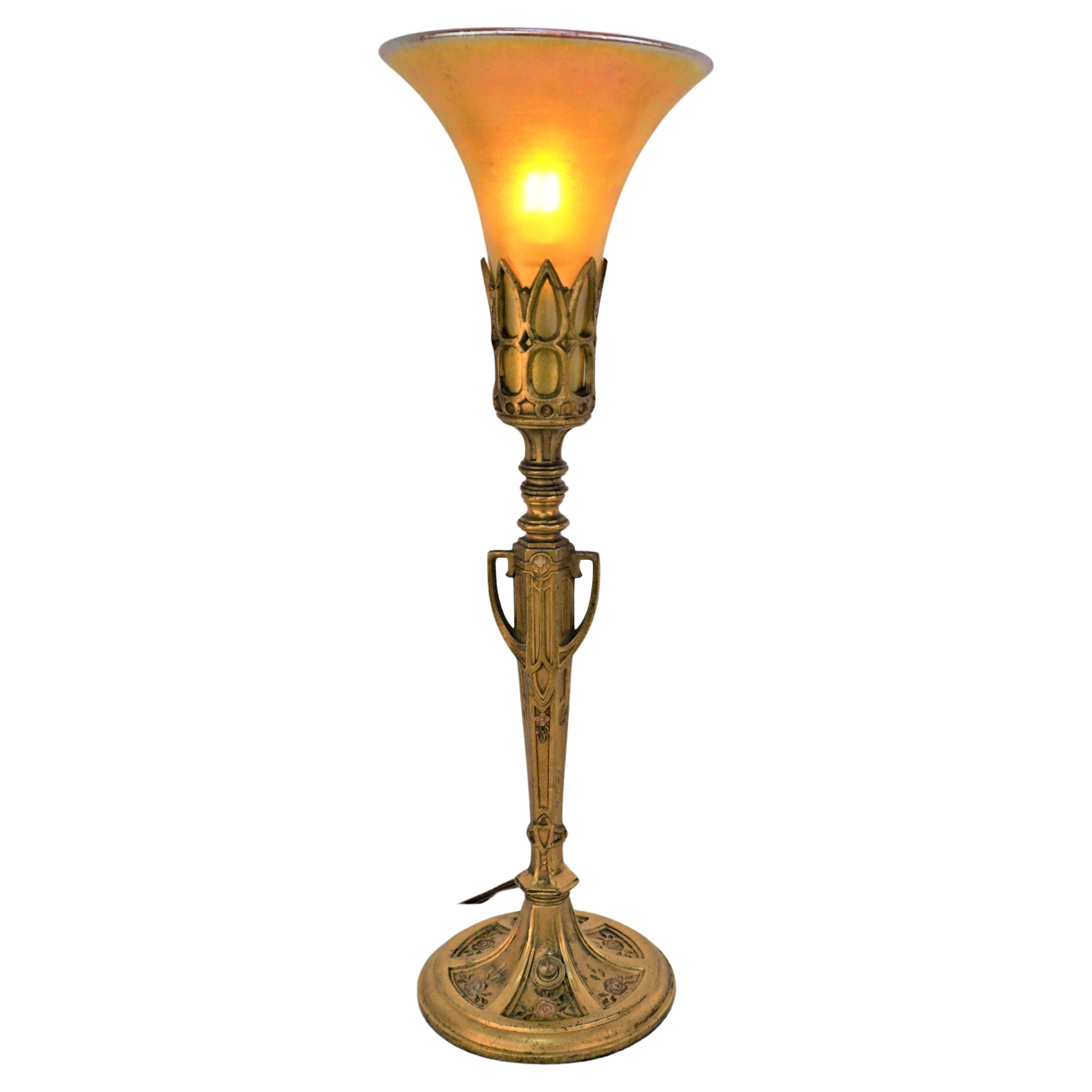 A pair of Art Deco style gilt metal table lamps with hand blown golden Tiffany style iridescent shades. This pair of lamps features art deco style flora paint gilt base with fabric cover cord.
