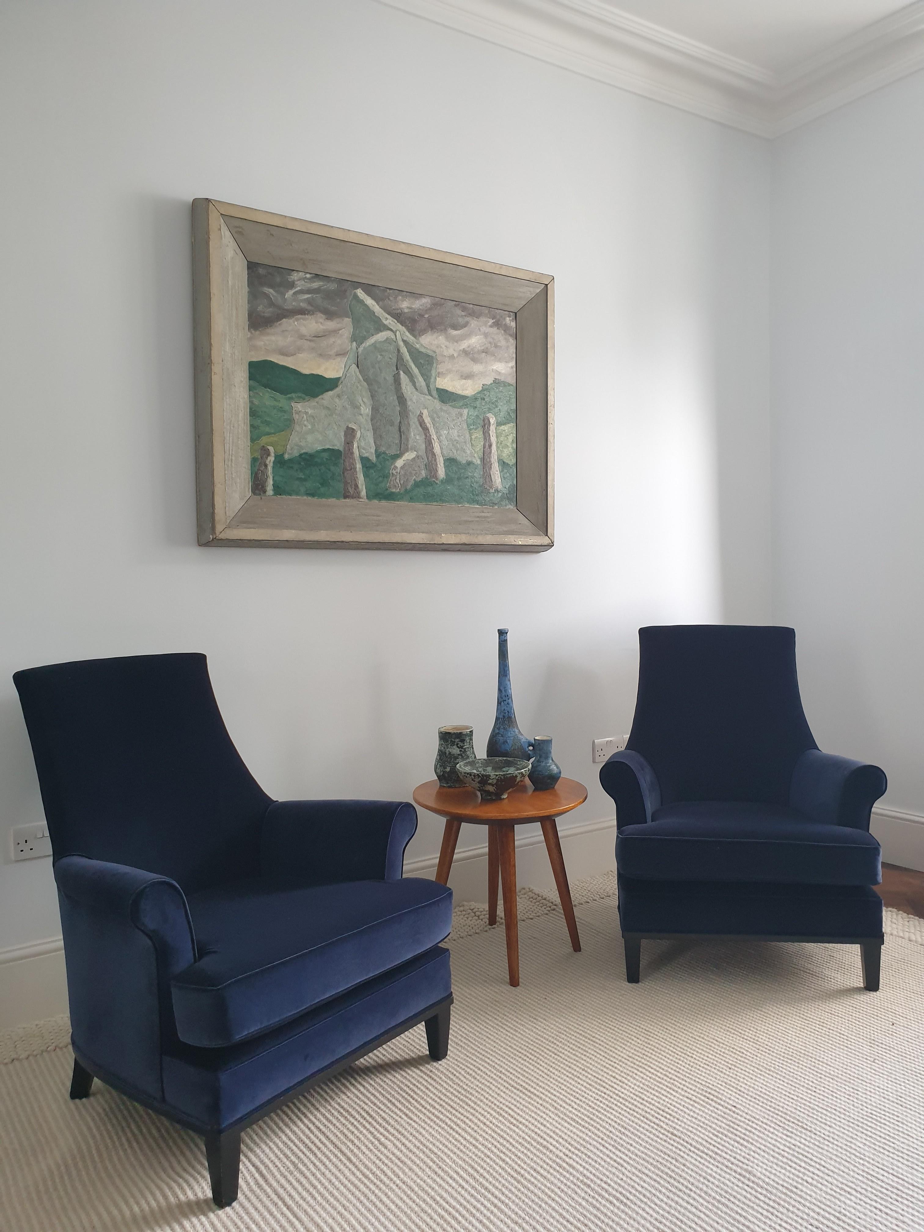 Pair of Mid-Century Modern upholstered armchairs with black lacquered legs and frame, reupholstered in good quality Swedish dark blue velvet. These very comfortable and elegant chairs have an attractive scrolled arm detail. They would fit perfectly