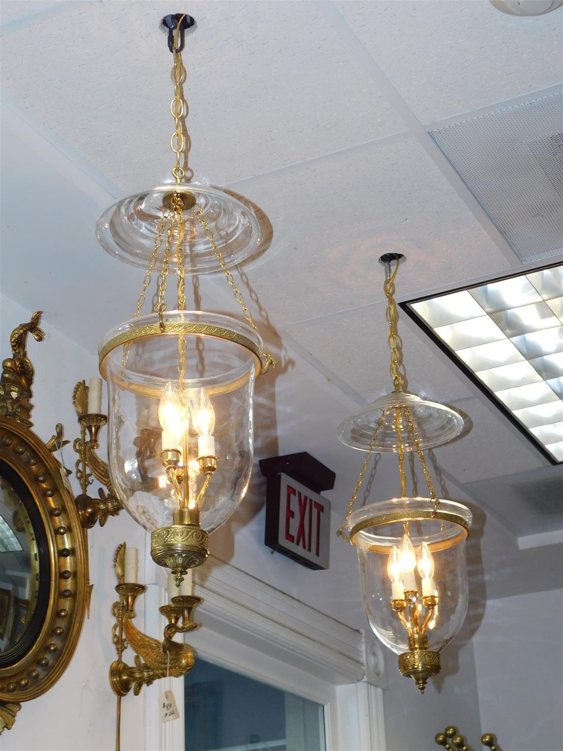 Pair of American brass and bell jar hanging glass foliage lanterns, Late 19th Century. Pair have a three light interior cluster.