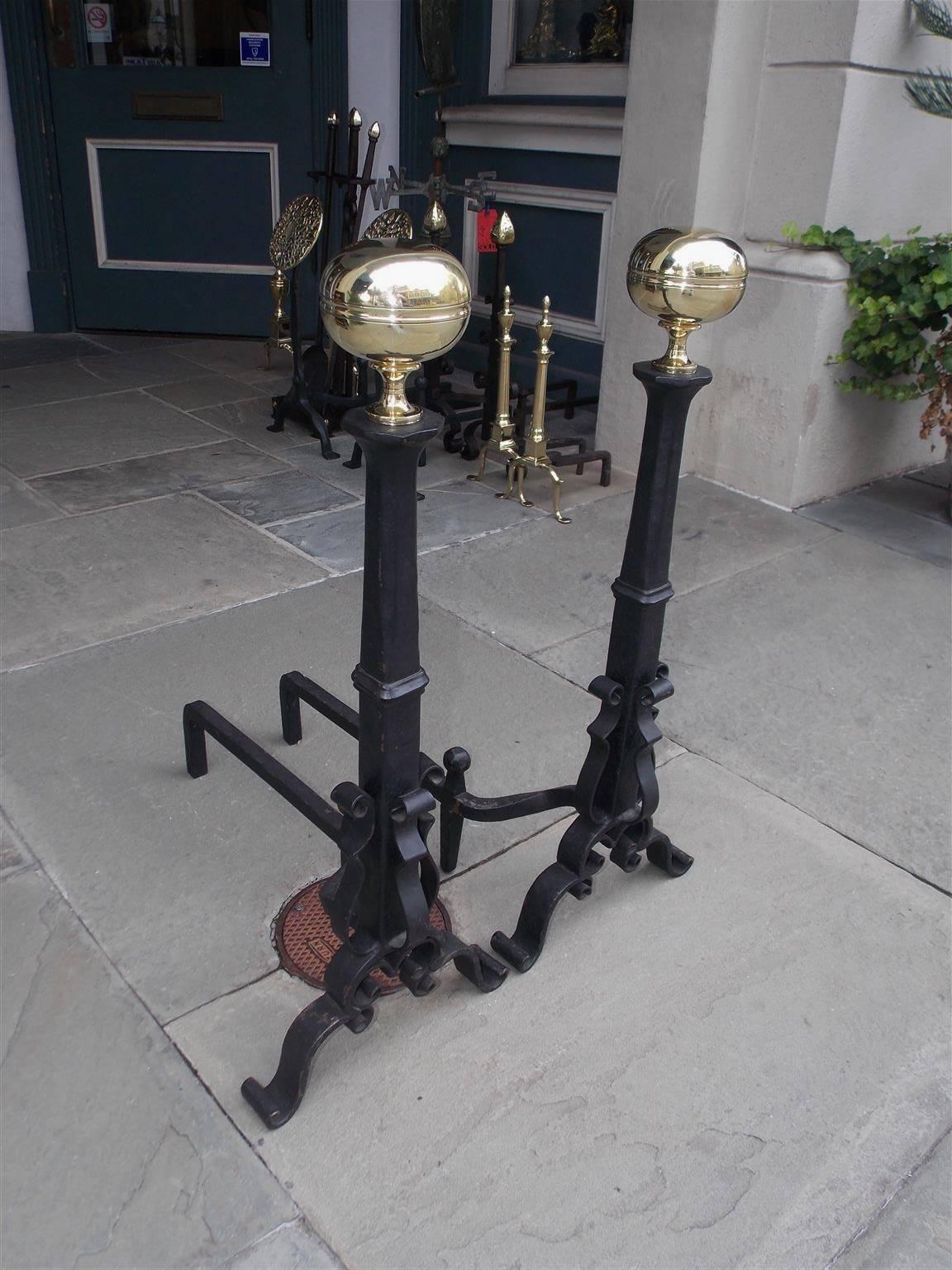 Pair of American brass and cast iron andirons with ball ringed finials, upper faceted centered columns, lower squared plinths, scrolled exterior spit hooks, matching ball log stops, and terminating on decorative scrolled legs, Mid-19th century.