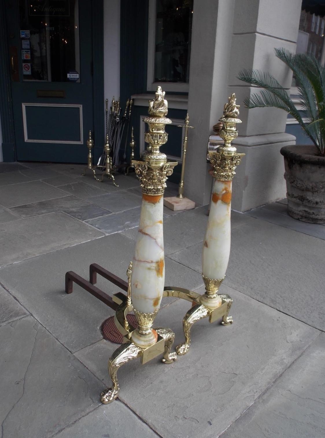 Pair of American brass and onyx andirons with flanking flame finial Urns, Corinthian capitals, centered bulbous onyx columns, squared floral plinths, matching flame finial log stops, and resting on acanthus scrolled ball and claw feet, Mid-19th