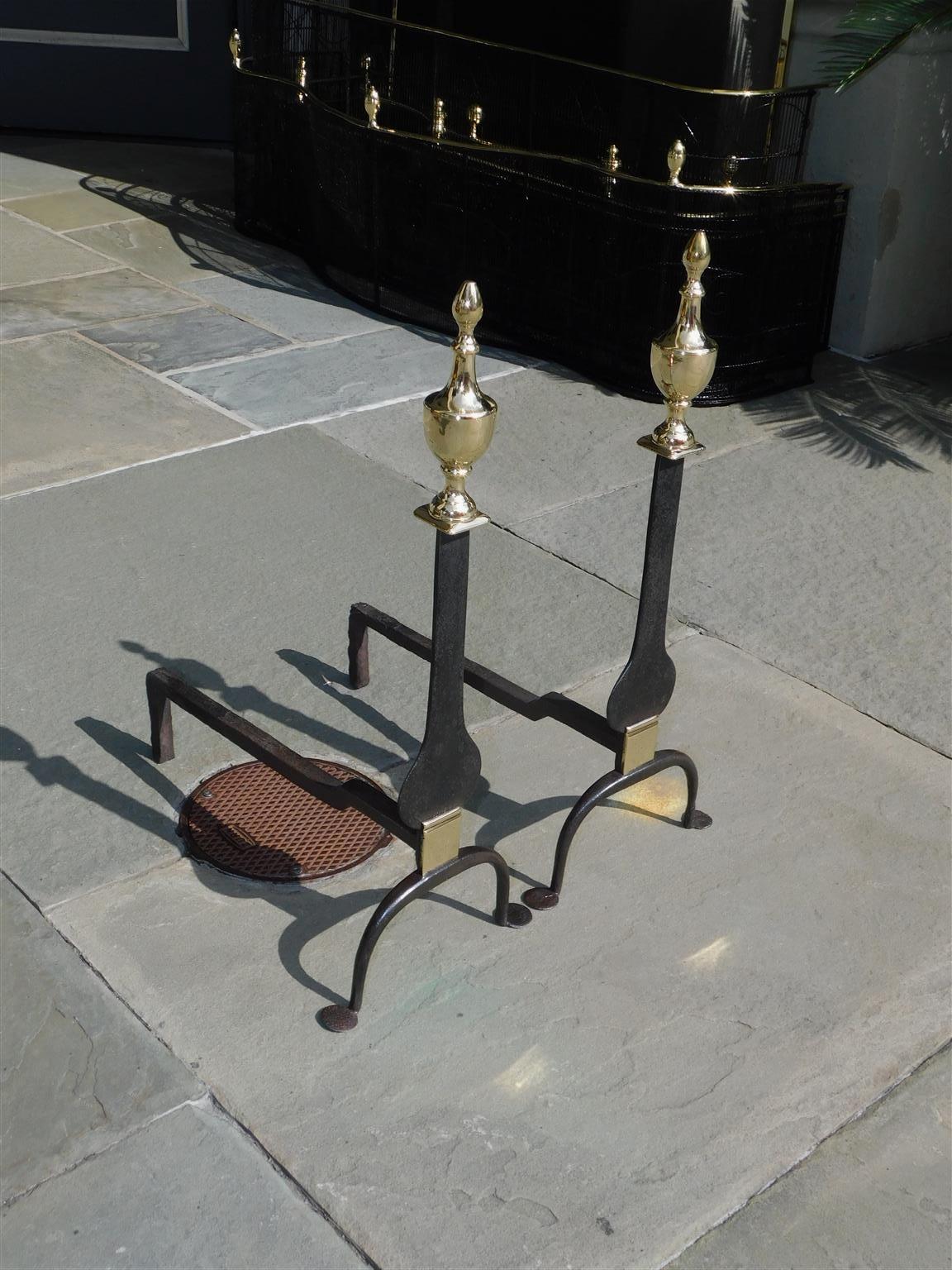 Paire de chenets américains en laiton et fer forgé, avec une urne flanquée d'un fleuron en forme de lame de couteau, avec des pieds à volutes et des pieds en penny. Début du 19e siècle