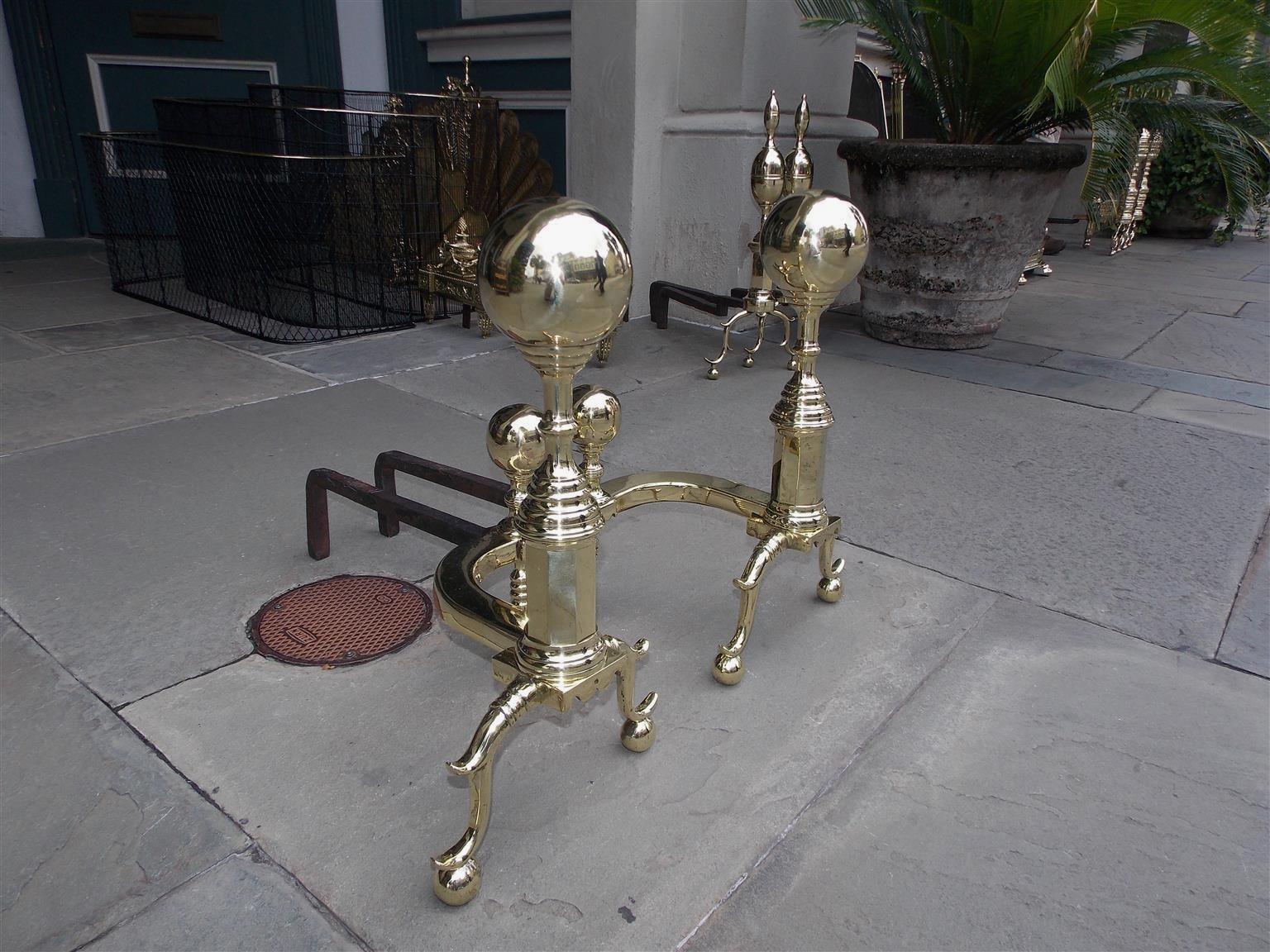 Pair of important size American brass ball finial andirons with turned ribbed centered columns, faceted ribbed plinths, matching ball log stops with ribbed brass legs, scalloped skirts, and terminating on spur legs with ball feet, Mid-19th century.