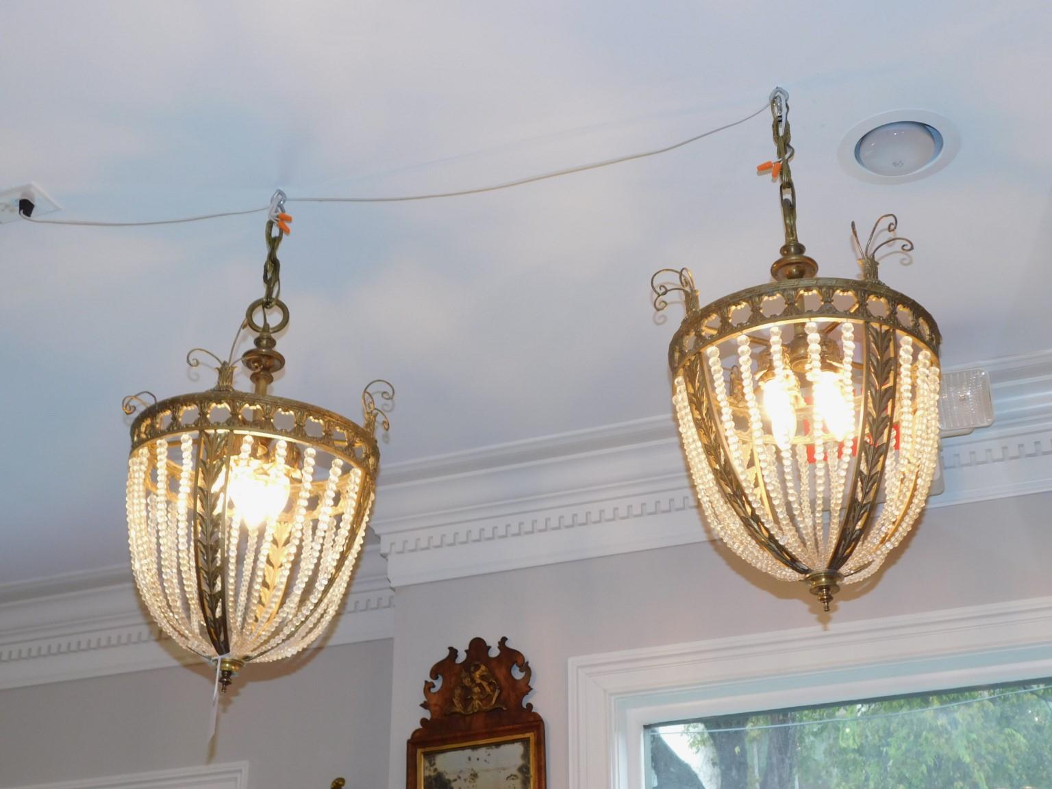 Coppia di lampadari americani in ottone fuso e cristallo perlato con volute e fogliame. Firmato Sterling Bronze Co., New York. Fine del XIX secolo / inizio del XX secolo 