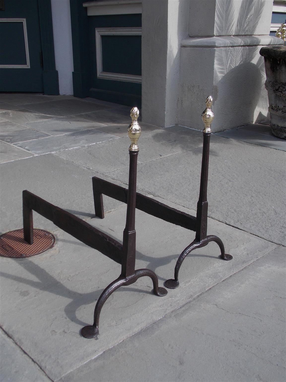Pair of American brass flame finial lemon top and wrought iron andirons with centered circular faceted columns, squared plinths, original dog legs, and terminating on scrolled legs with penny feet. Late 18th Century