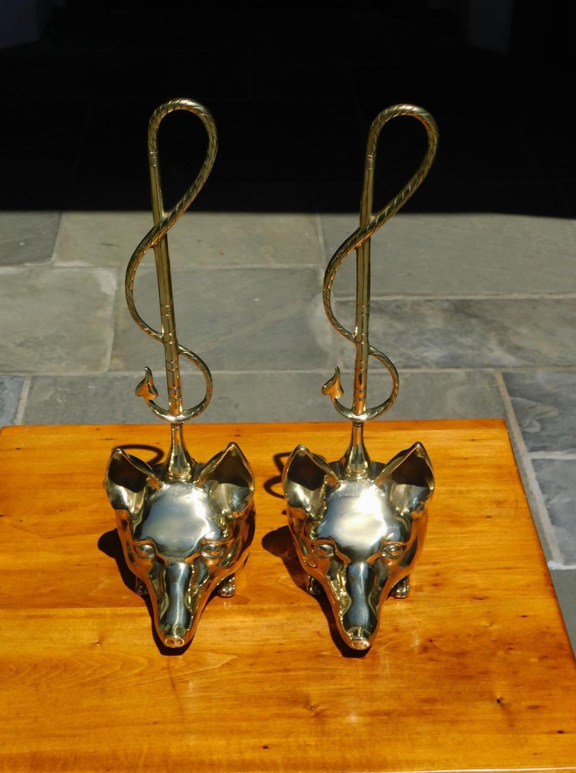 Pair of American brass fox head doorstops with decorative chased intertwined carrying handles, late 19th century.