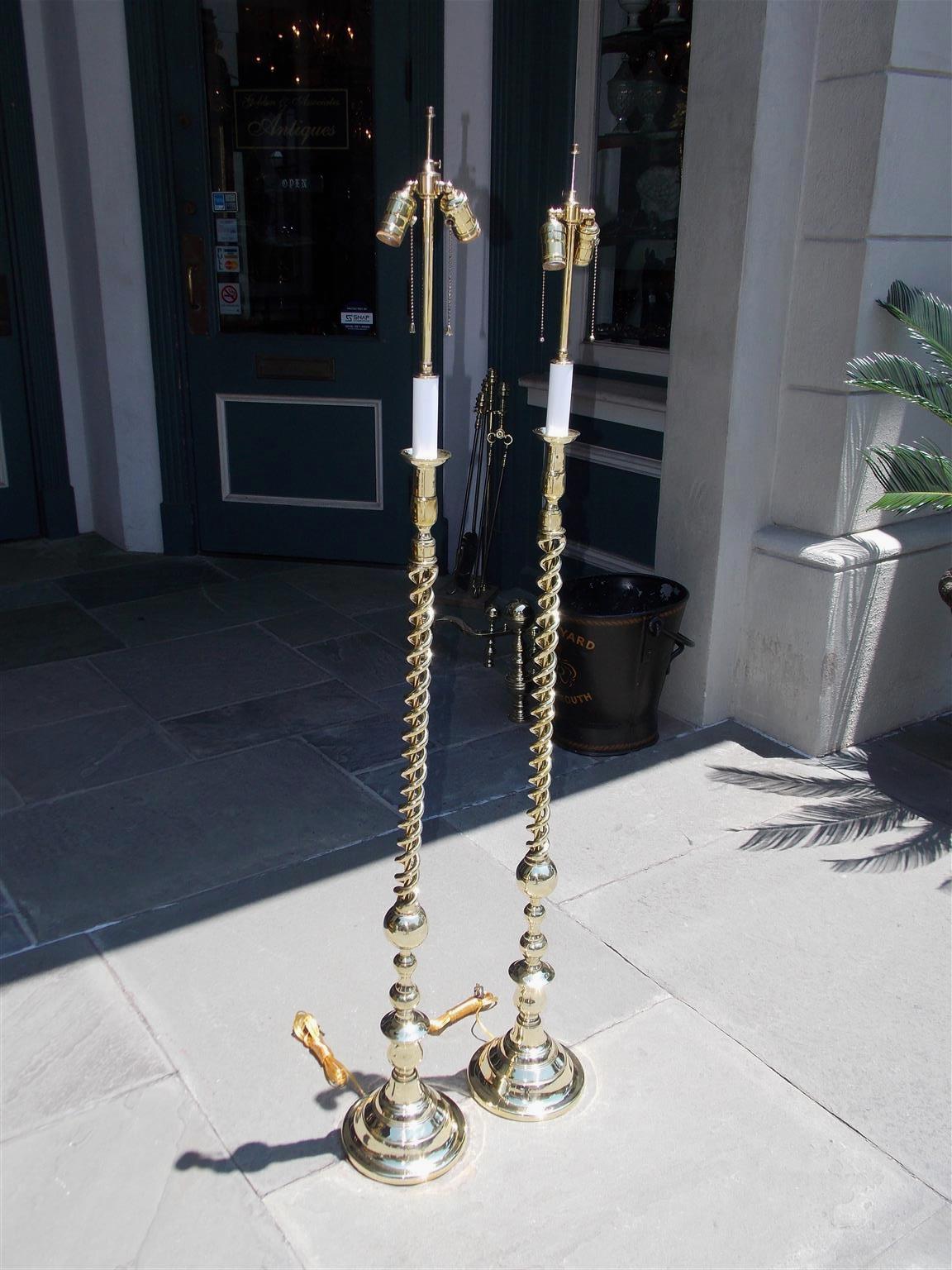 Pair of American brass spiral and bulbous form floor lamps resting on circular step back bases, Late 19th century. Pair were originally candle powered and have been electrified.