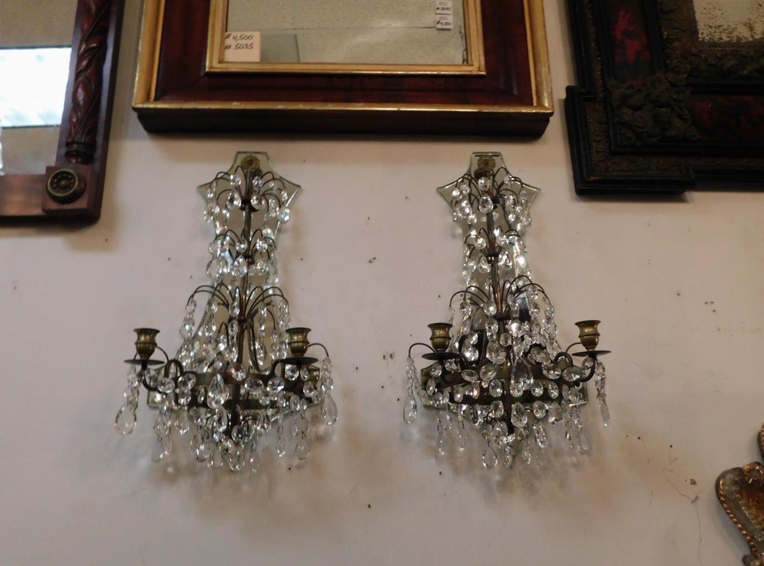Pair of American bronze and crystal scrolled two arm mirrored wall sconces with flanking gilt foilate medallions. Sconces are candle powered but can be electrified if desired, Late 19th century.