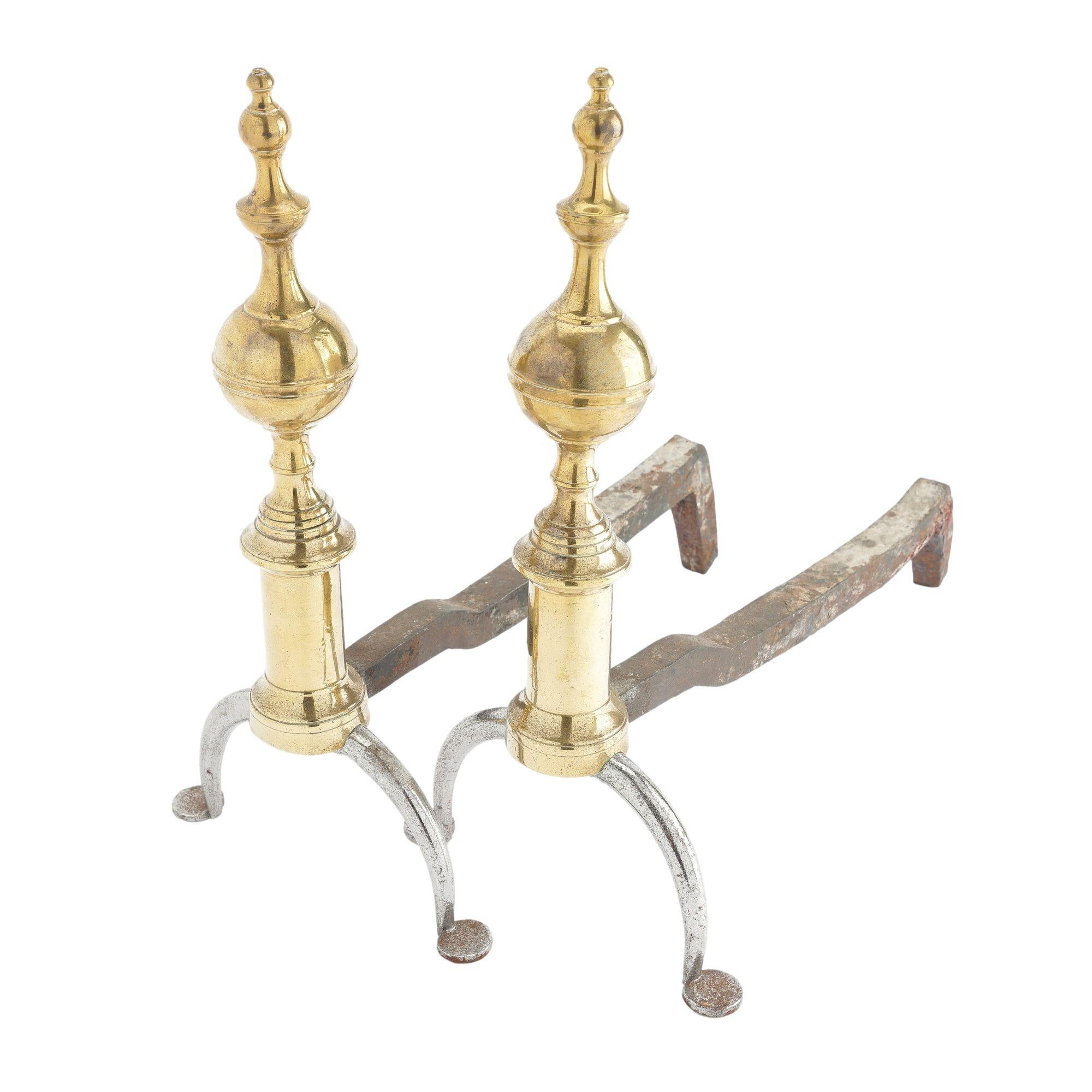 Pair of cast brass and forged iron steeple top andirons. Note the use of a forged iron leg with penny feet, which is an hallmark of the conservative use of brass during the period of the War of 1812.

New York, circa 1812-15.