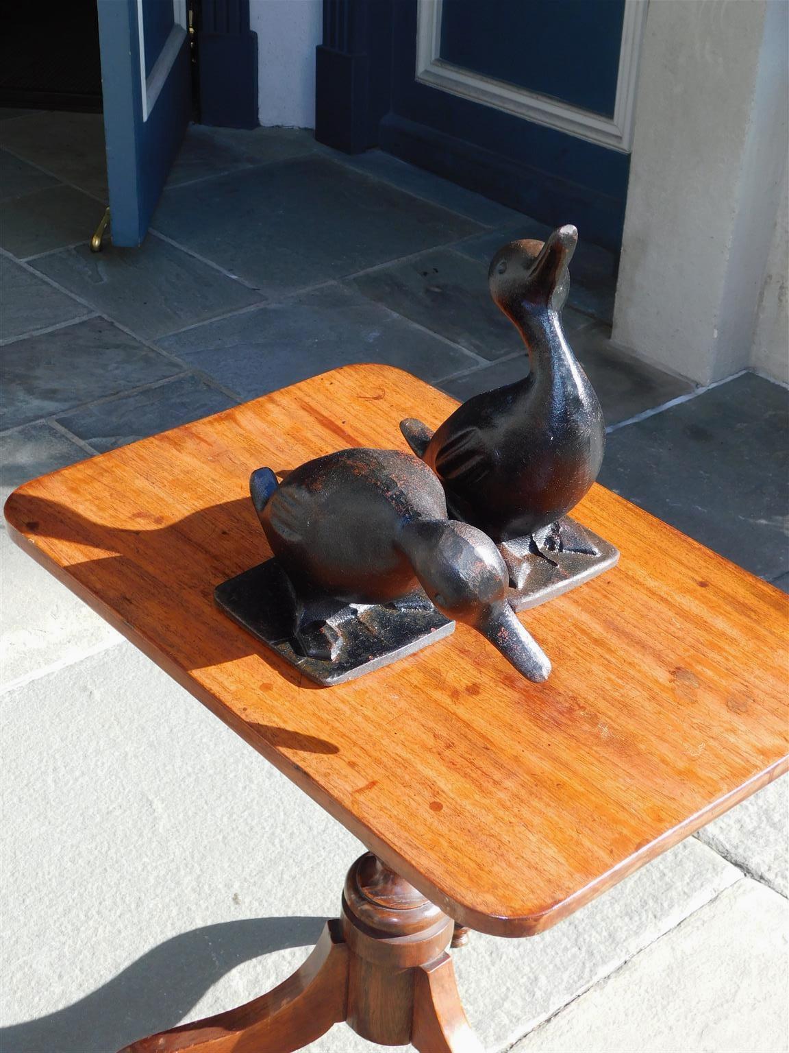 Pair of American cast iron hand painted preening ducks resting on squared bases. Late 19th Century.