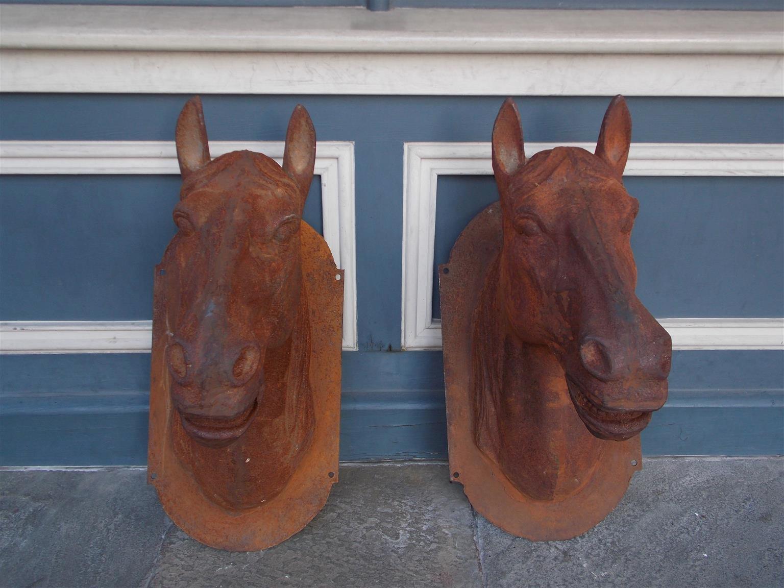 Pair of American cast iron horse heads with oval mounts, Mid-19th century. Great for mounting on Stable, Gates, or Entrance Columns.