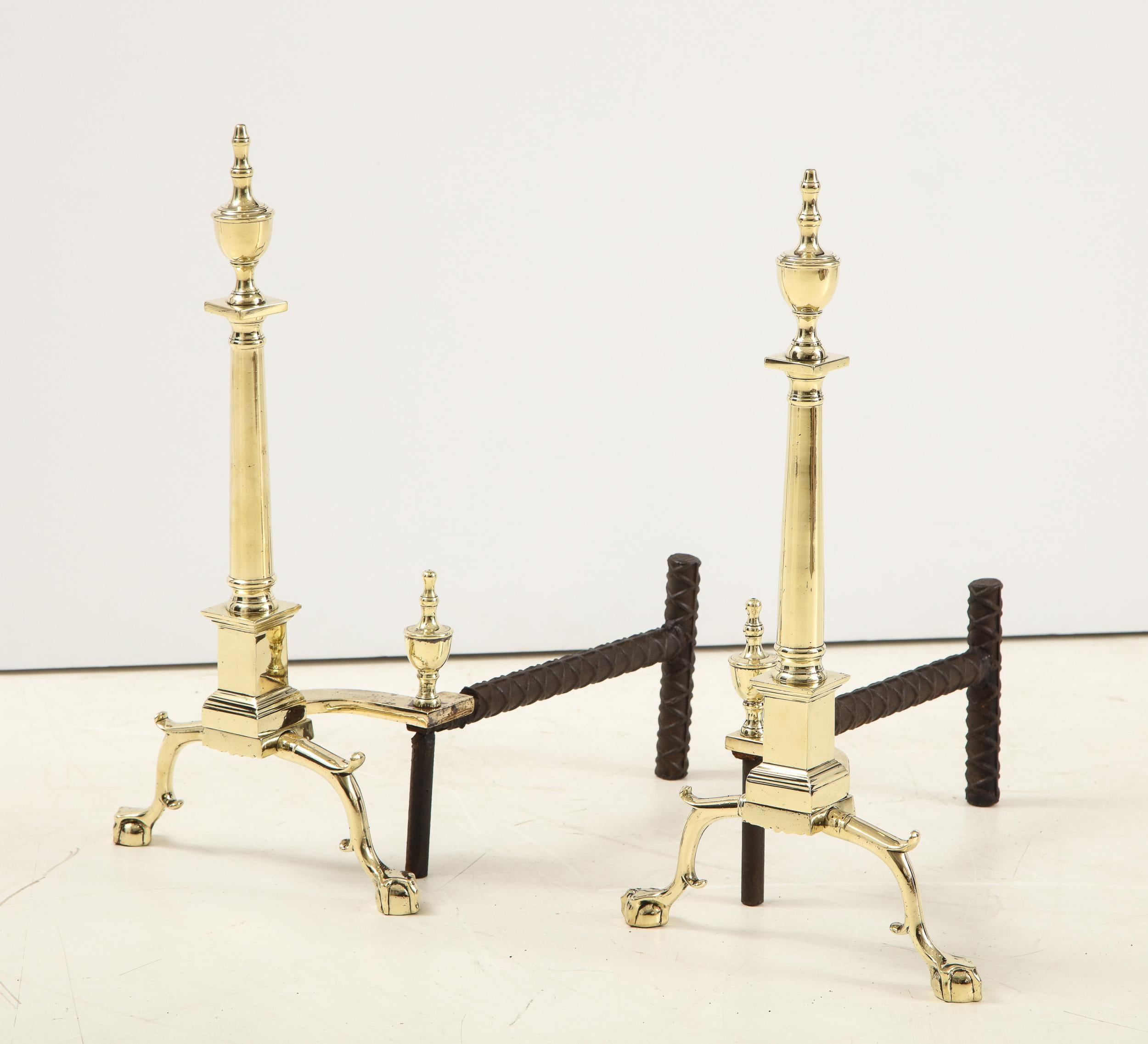 Good pair of American Classical style andirons having double knob urn finials over Doric column shafts, standing on plinth support over pair of scrolled and spurred legs ending in ball and claw feet.