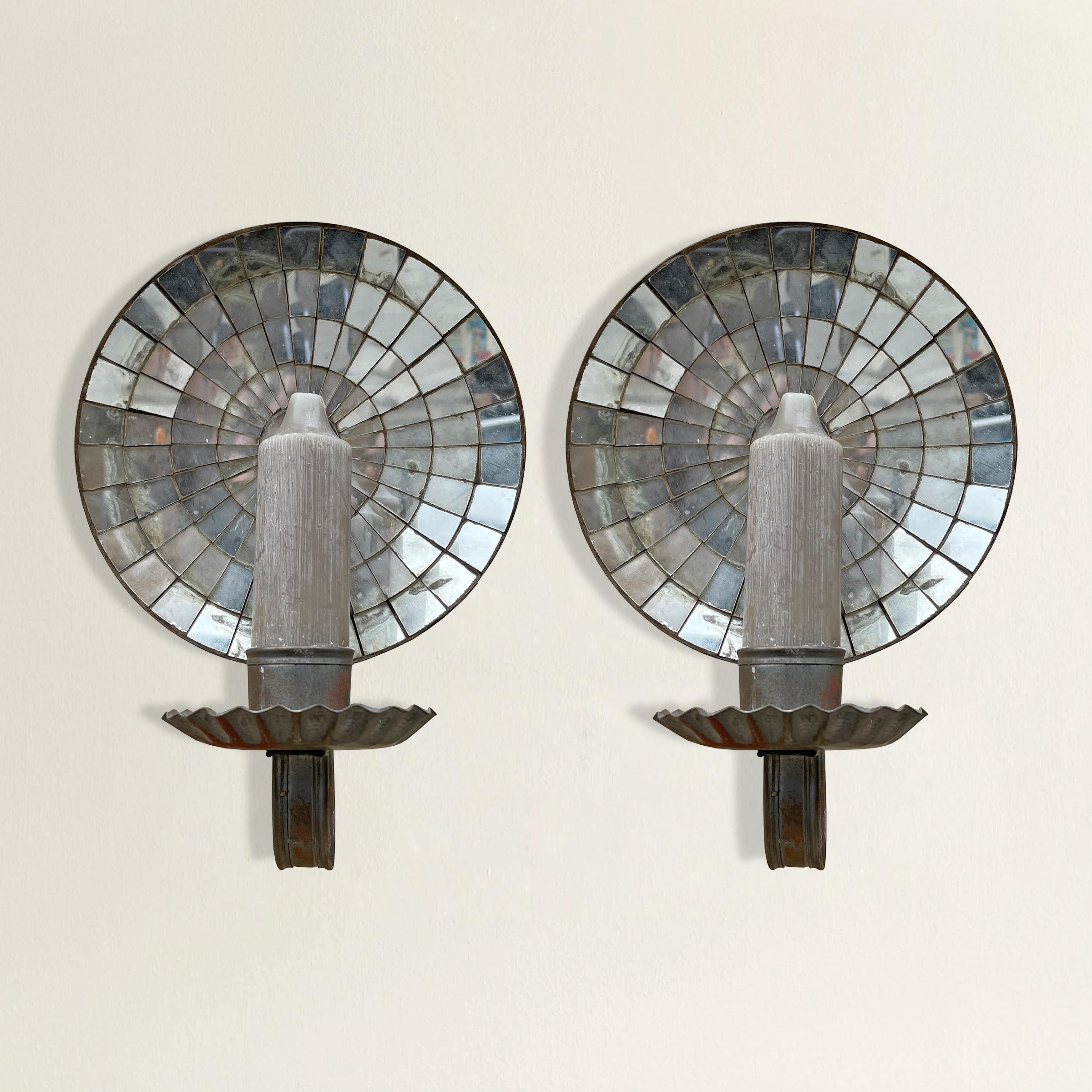 A striking pair of American tin candle sconces, each with a convex mirrored reflector and ruffled candle cup. While they were designed to work with candles and have never been electrified, it would be fairly simple to convert them to electricity.