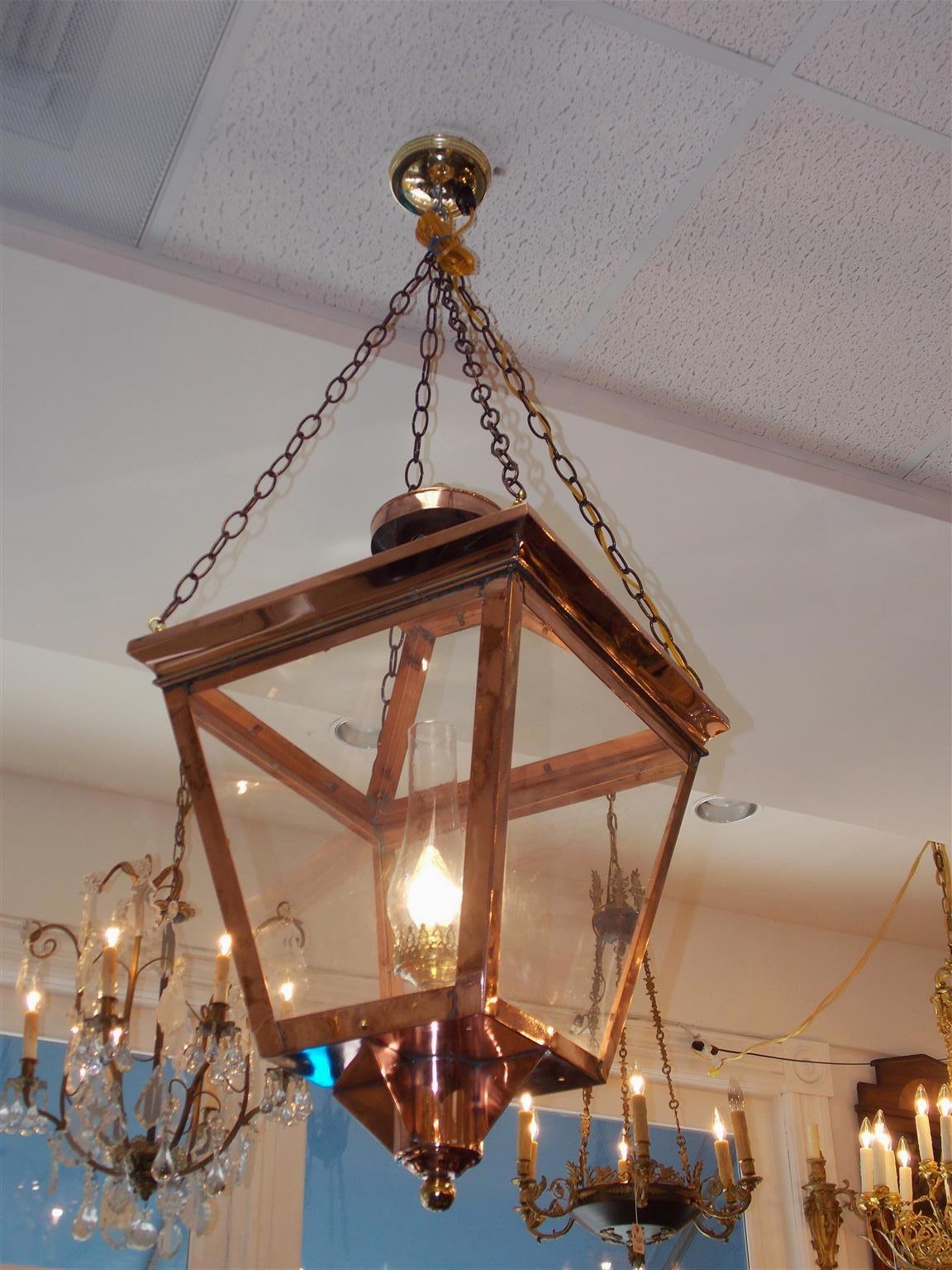 Pair of American copper and brass hanging glass lanterns with circular bulbous vented finials, four sided glass panels, locking hinged door, and electrified with a single brass centered light and chimney. Early 19th century. Lanterns were originally