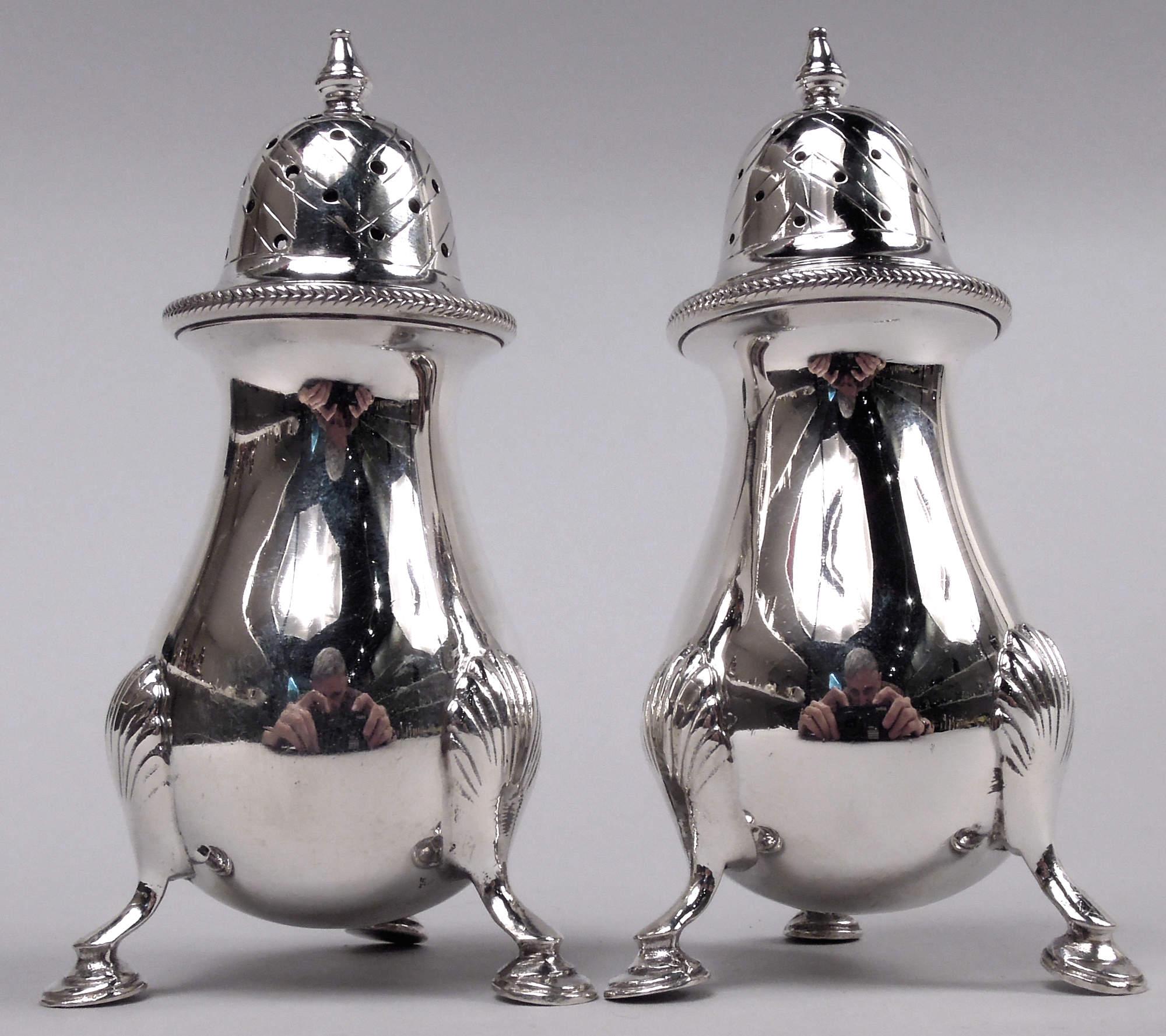 Coppia di shakers classici edoardiani in argento sterling. Ciascuno: Ciotola a balaustro con tre supporti per zoccoli montati su conchiglia. Coperchio a cupola e traforato con terminale vasiforme e ornamento a chevron inciso; stesso bordo.