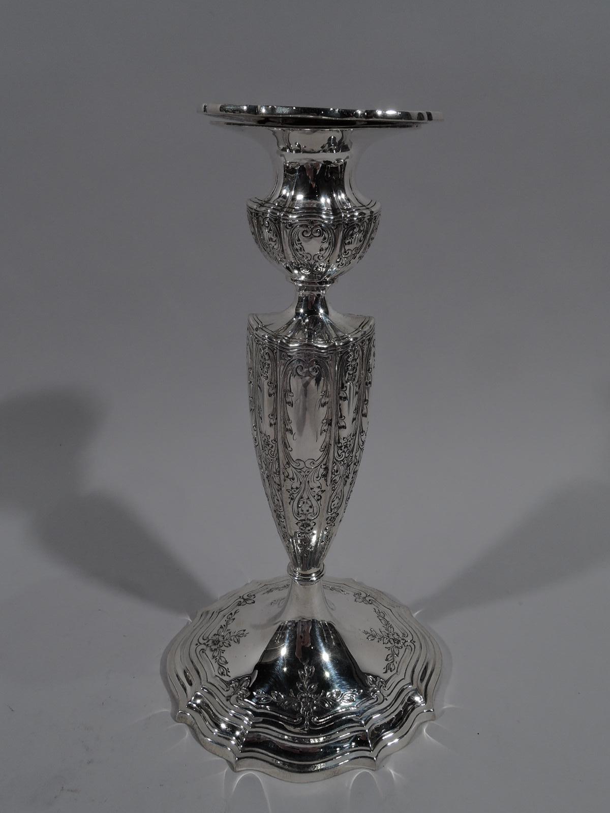 Pair of Edwardian Regency sterling silver candlesticks, circa 1910. Each: Ovoid with lobed shaft on raised and stepped foot; socket bellied with detachable bobeche. Bobeche and foot rim have scrolled rims. Engraved scrolling ornament with flowers